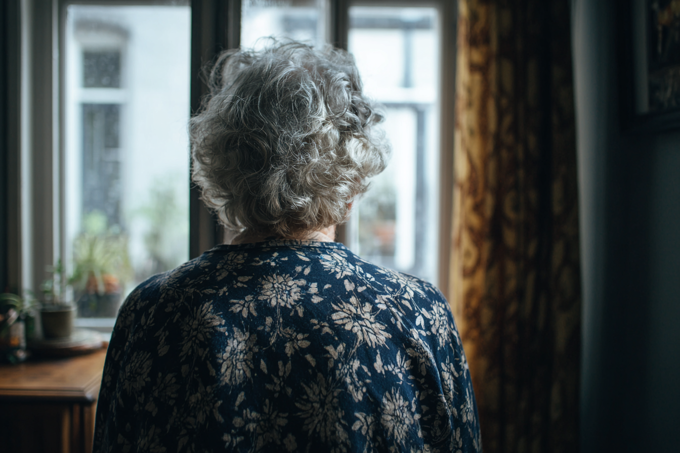 Una mujer mayor junto a una ventana | Fuente: Midjourney