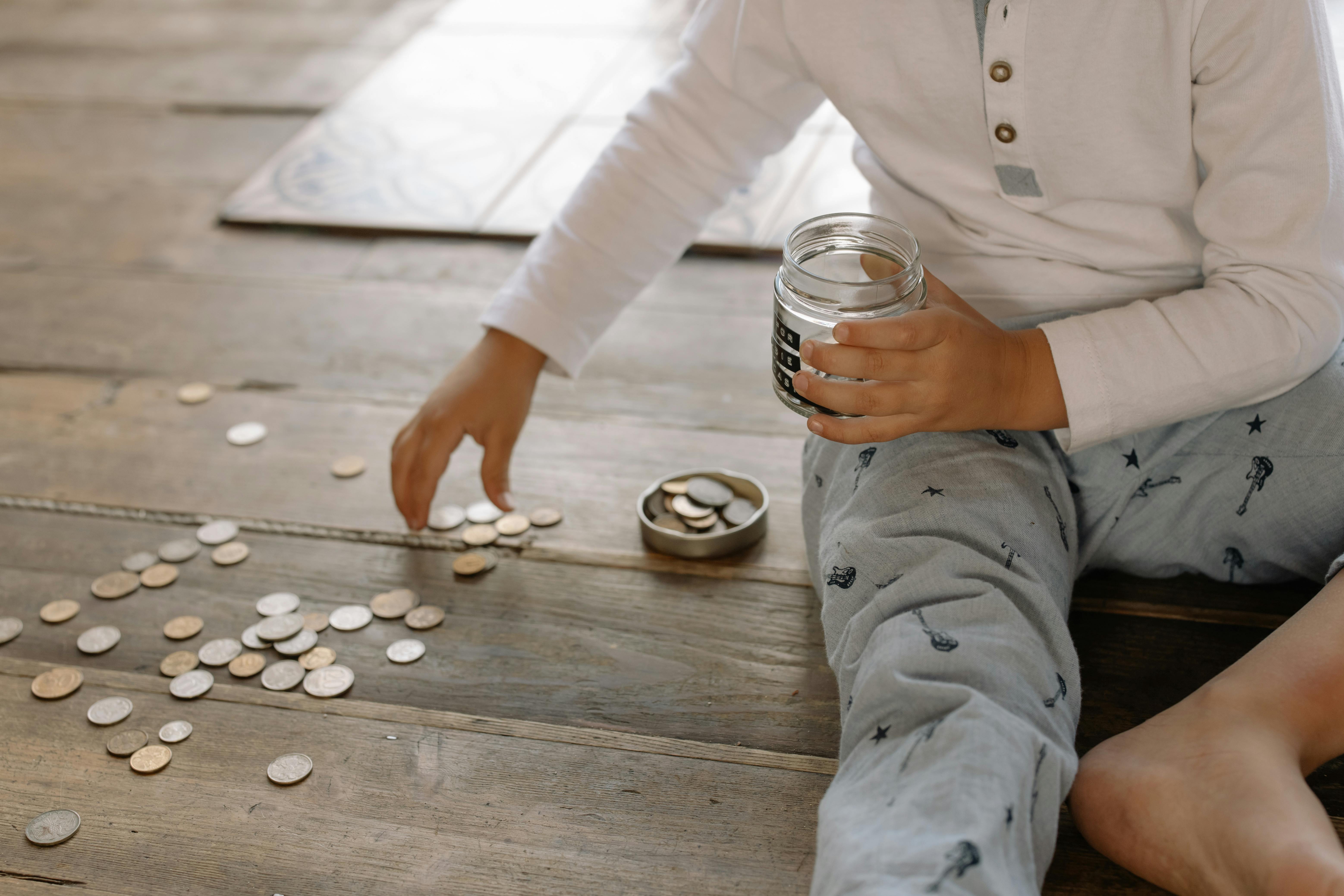 Un niño metiendo monedas en un tarro de cristal | Fuente: Pexels