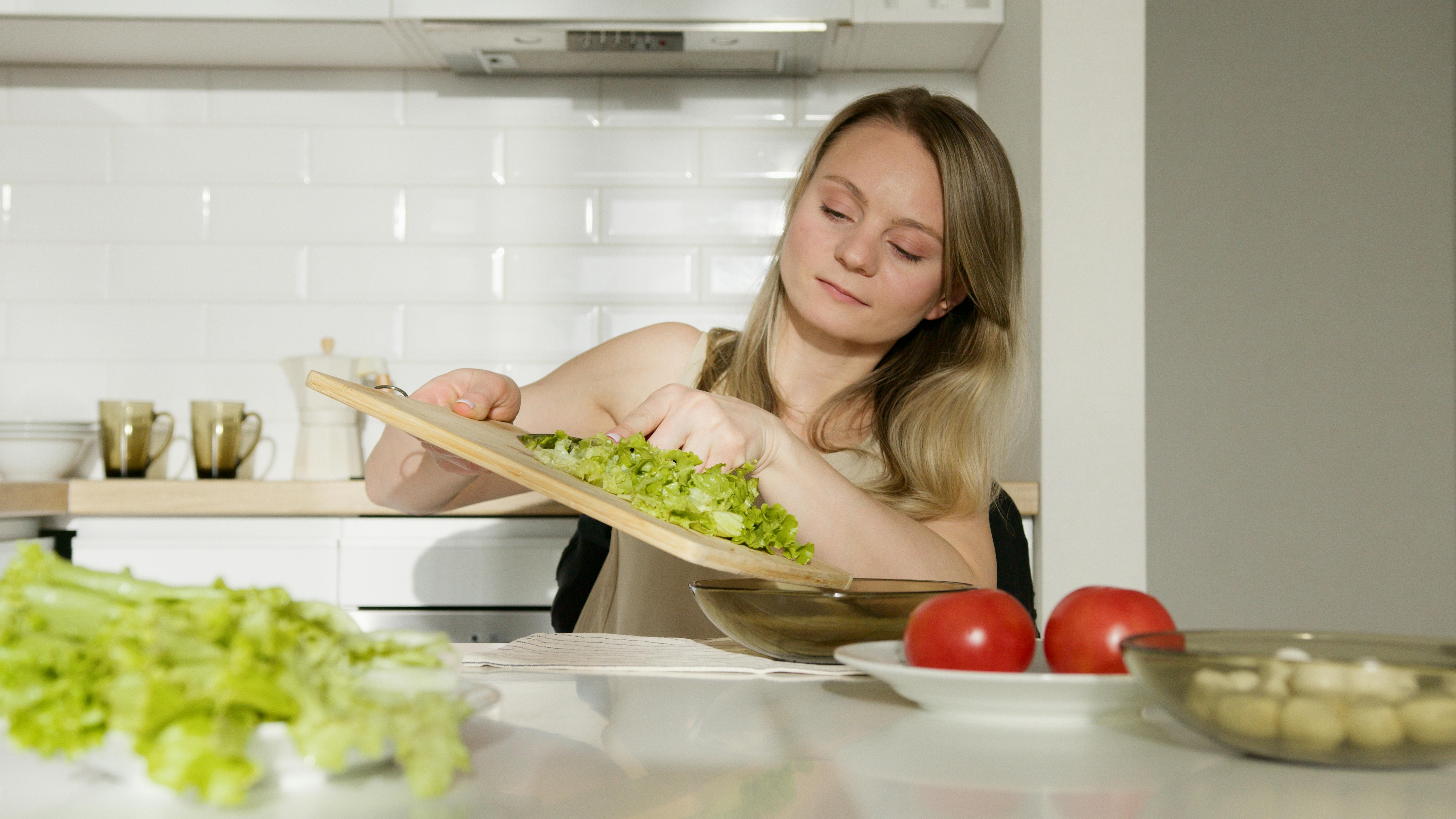 Mujer joven haciendo ensalada | Fuente: Pexels