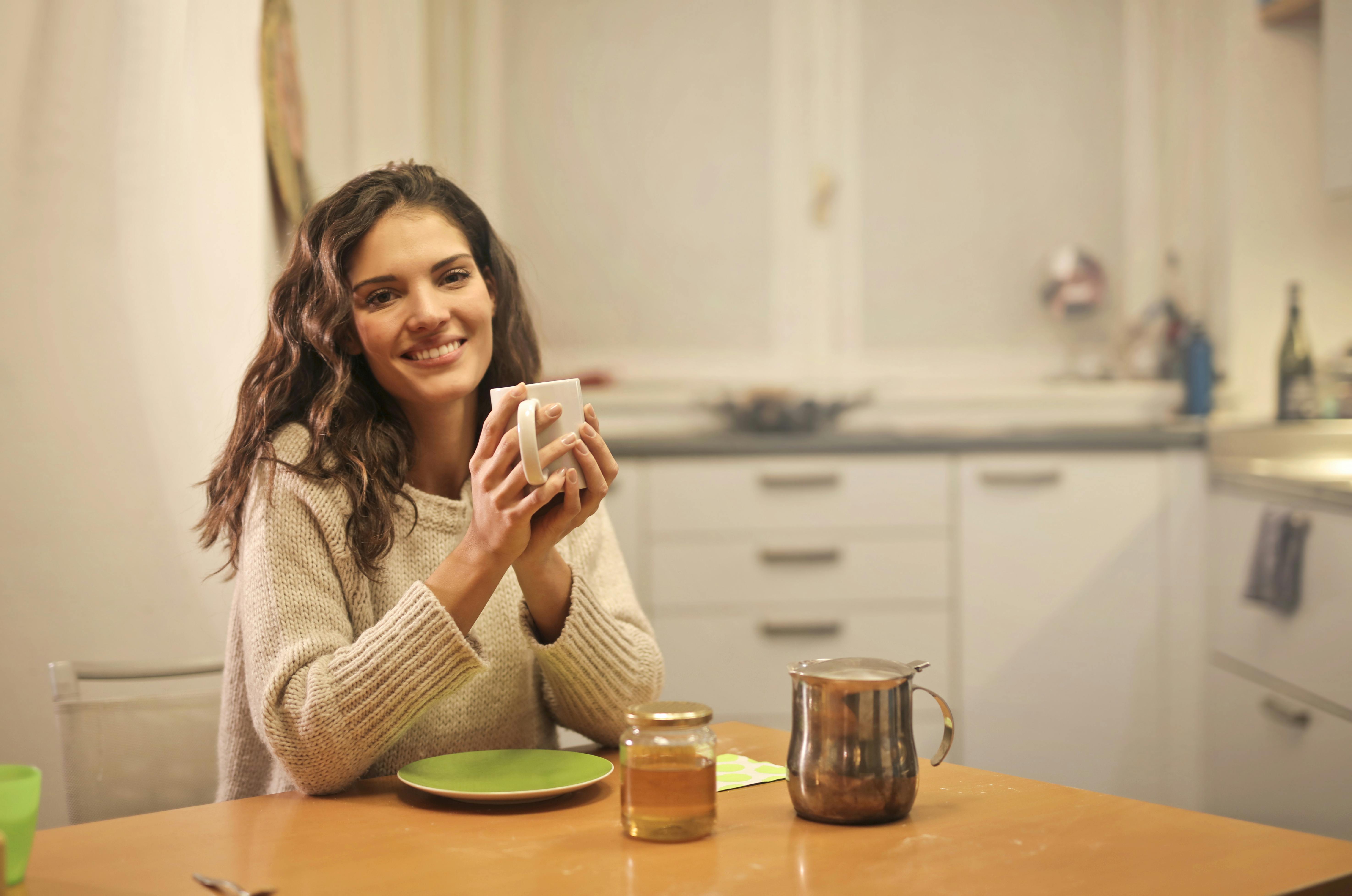 Una mujer sonriendo mientras sostiene una taza | Fuente: Pexels
