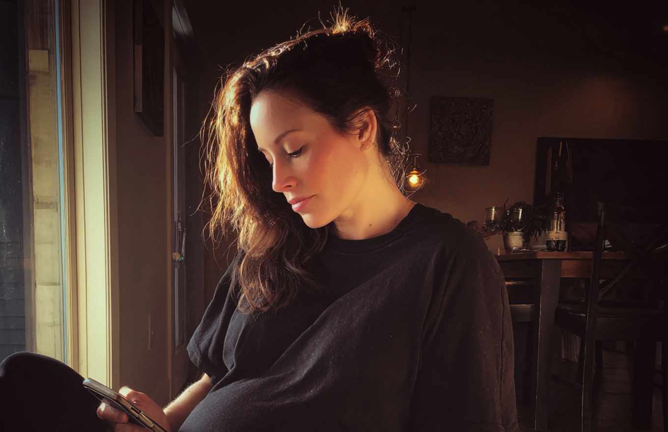 Una mujer cansada usando su teléfono | Fuente: Midjourney
