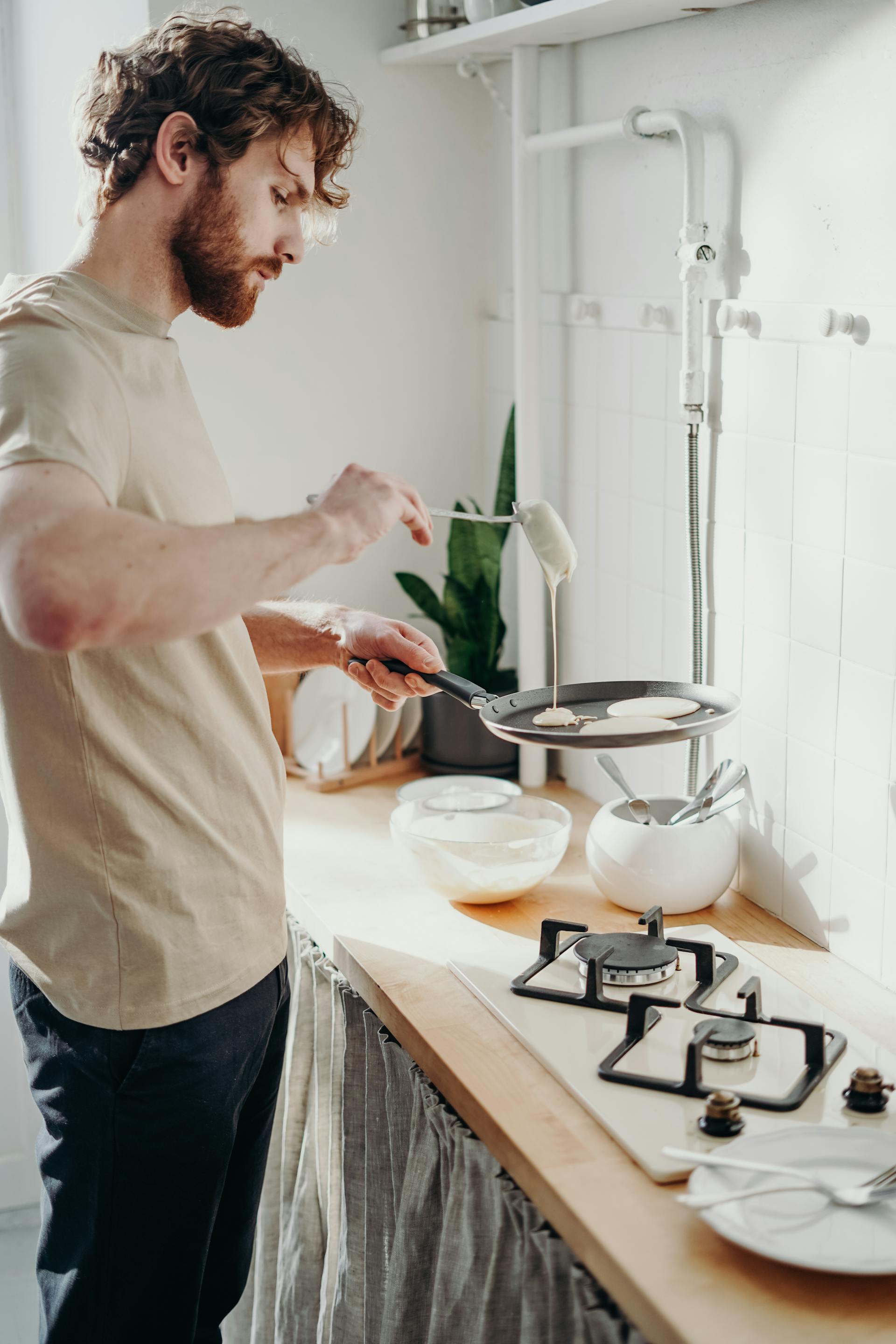 Un hombre haciendo tortitas en la cocina | Fuente: Pexels