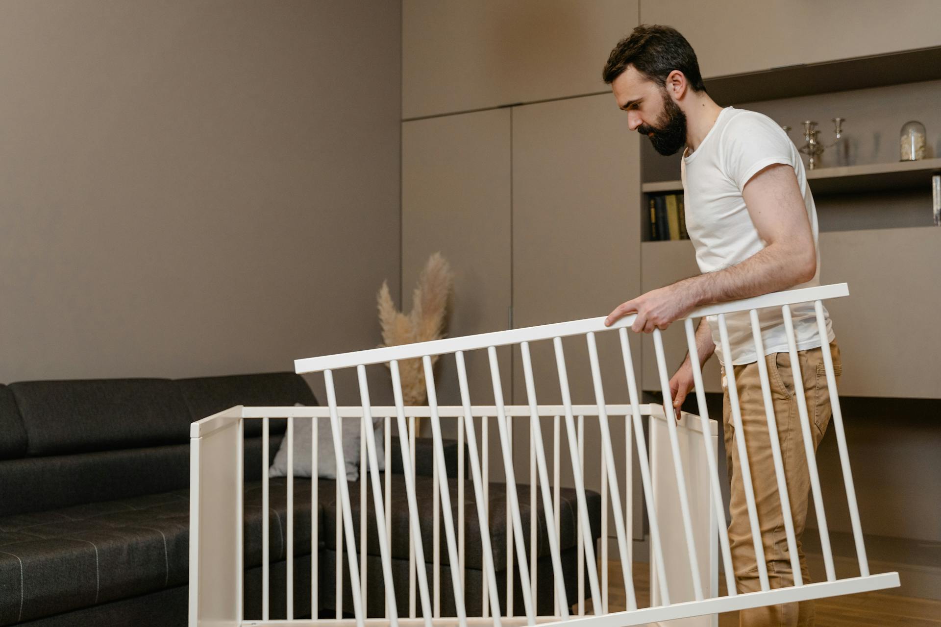 Hombre sujetando piezas de una cuna de bebé desmontada | Fuente: Pexels