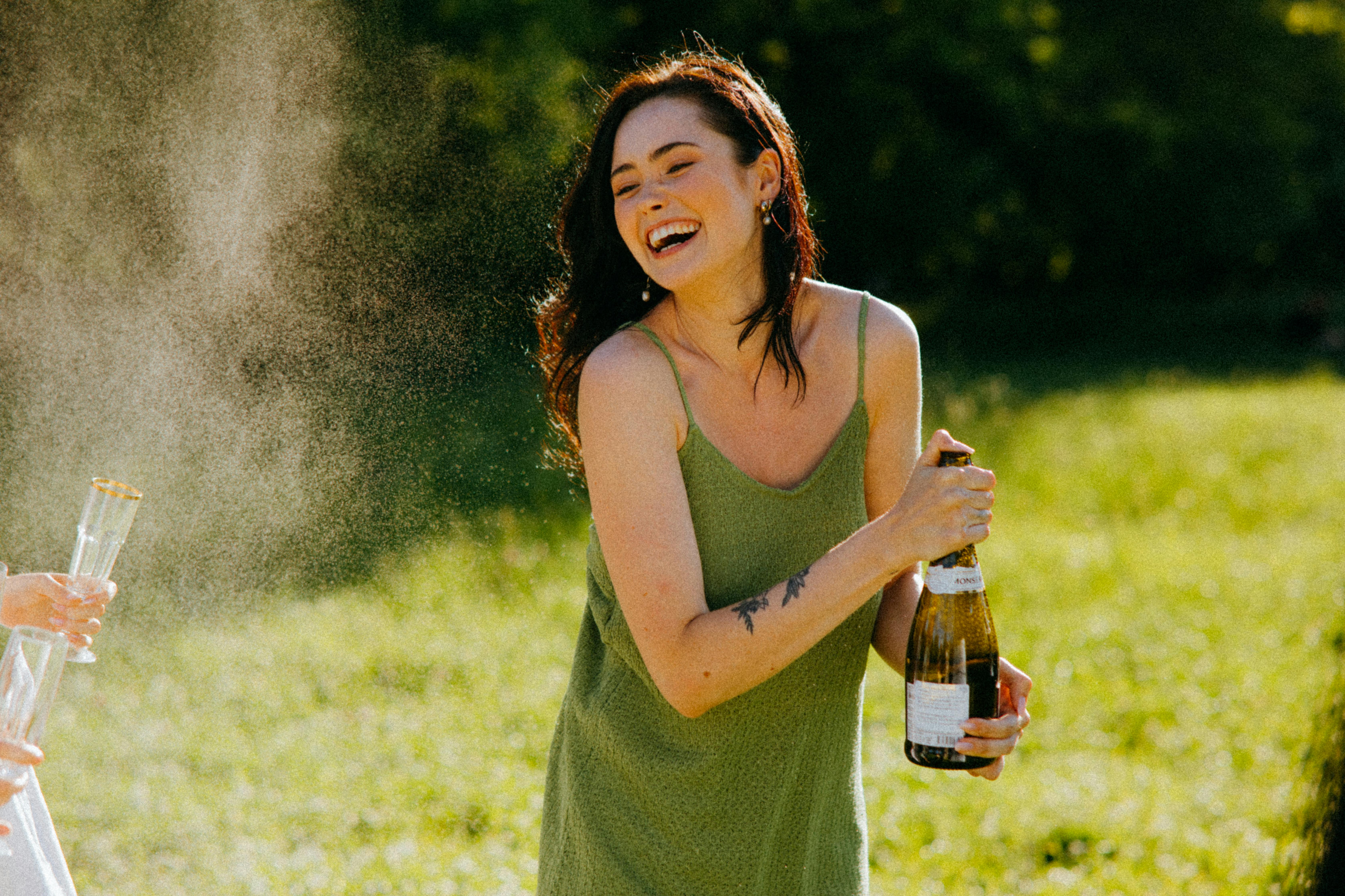 Una mujer riendo mientras sostiene una botella | Fuente: Pexels