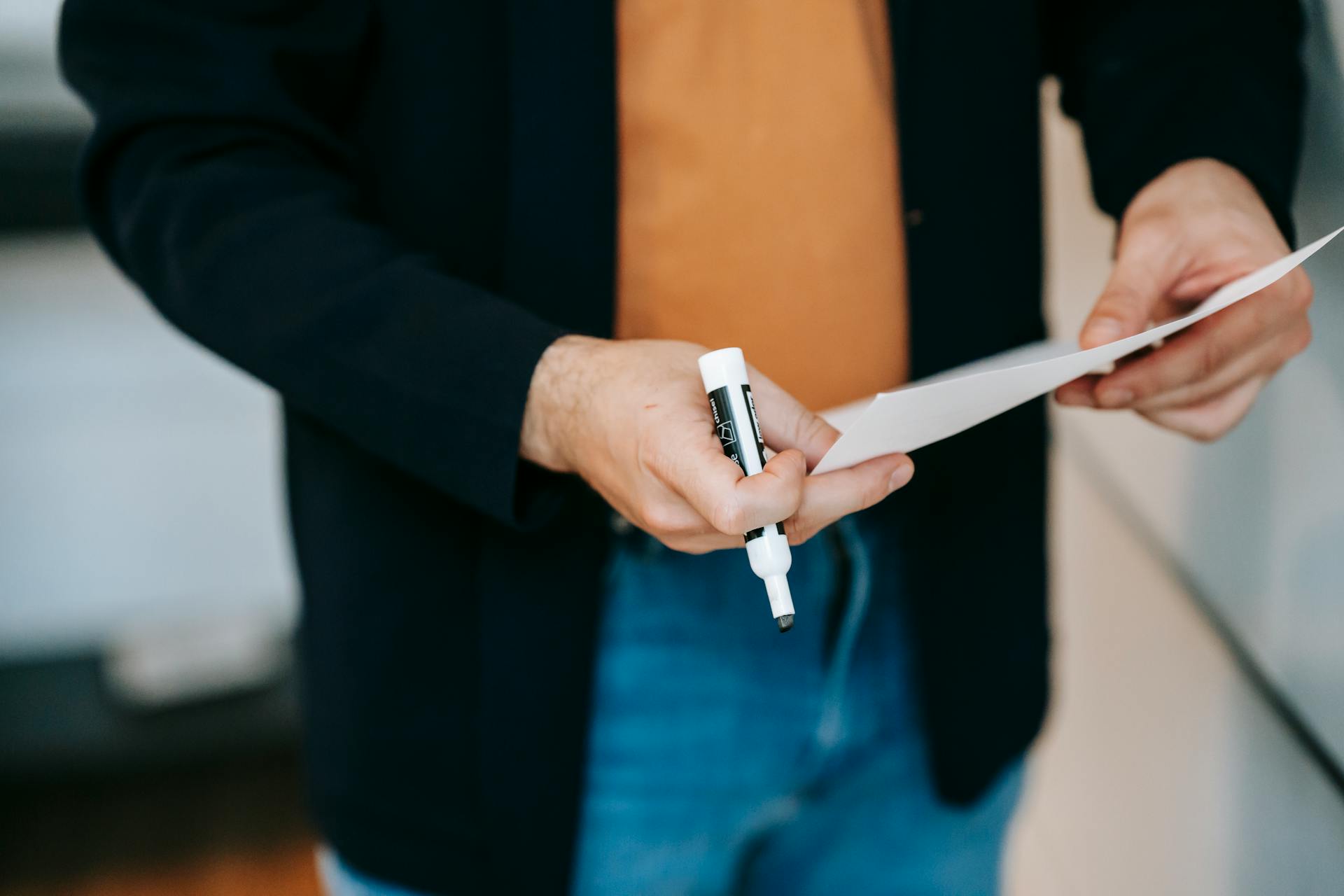 Un hombre con un rotulador y un trozo de papel | Fuente: Pexels