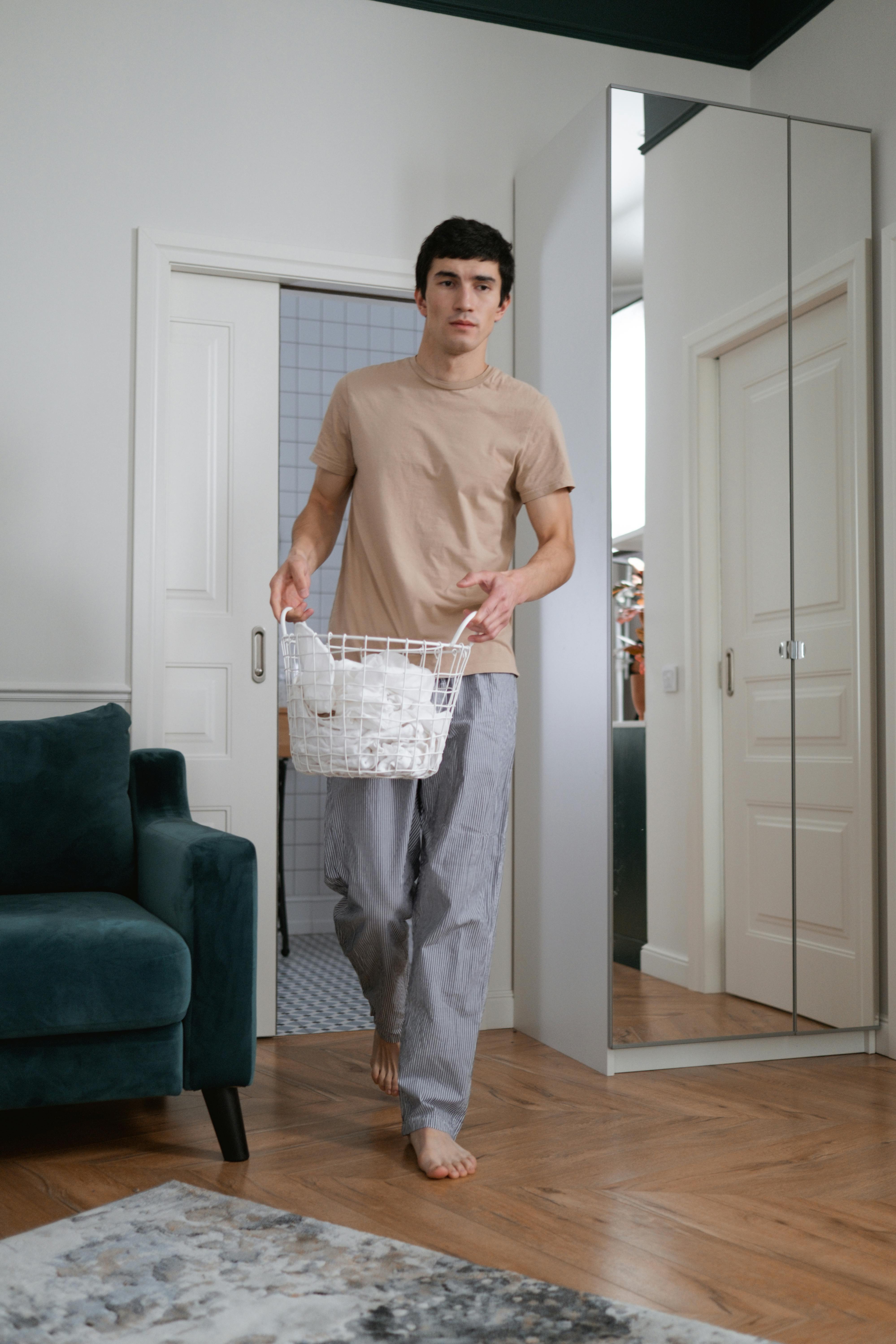 Hombre llevando una cesta dentro de la casa | Fuente: Pexels