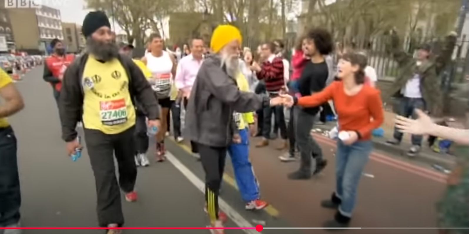 Fauja Singh estrecha la mano de los espectadores durante el Maratón de Londres. De un vídeo del 6 de agosto de 2012. | Fuente: YouTube/BBC