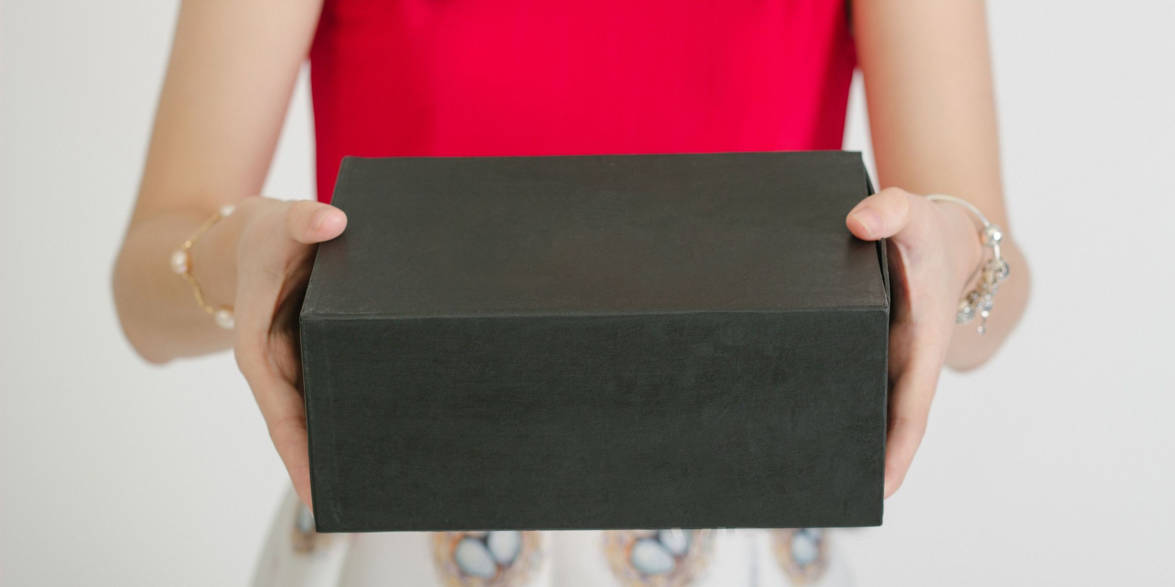 A close-up of a woman holding out a gift box | Source: Pexels