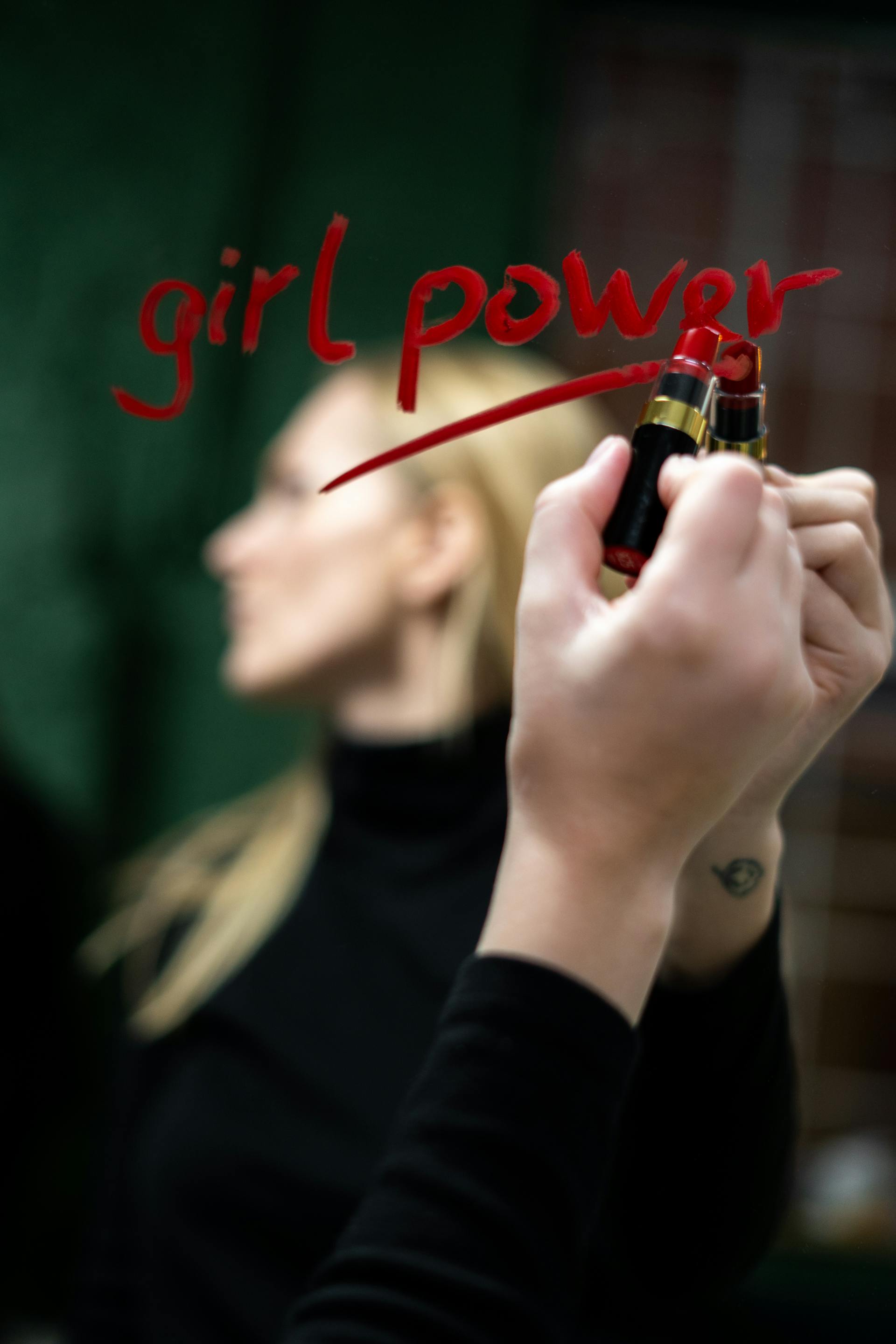Una mujer escribiendo en un espejo con pintalabios rojo | Fuente: Pexels