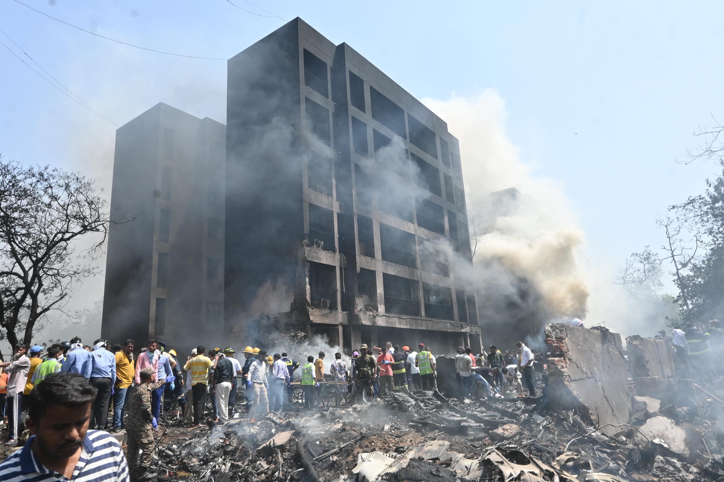 El humo se eleva desde un edificio dañado mientras la gente se reúne en el lugar del accidente en Ahmedabad, India, el 12 de junio de 2025 | Fuente: Getty Images