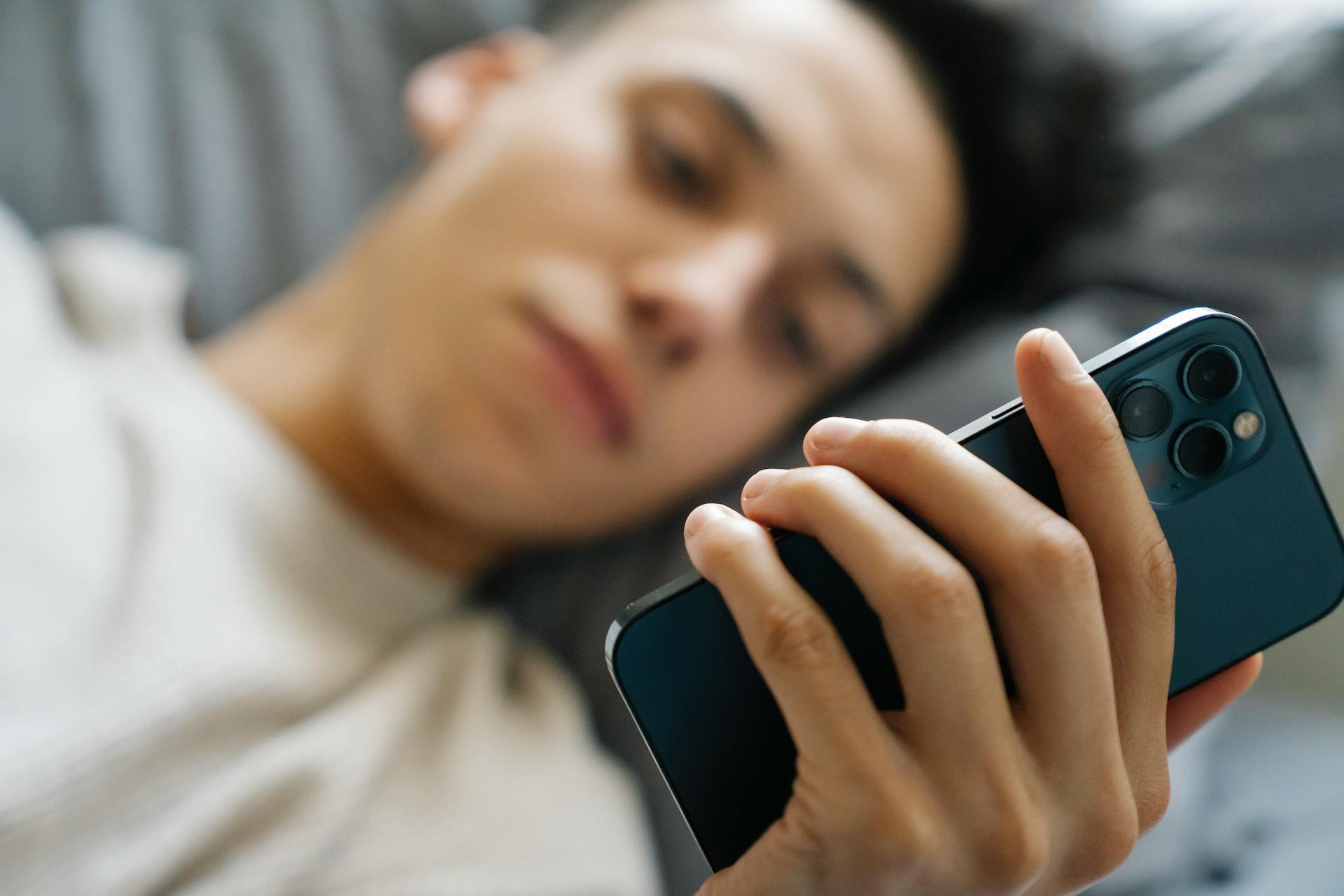 Un joven usando su teléfono en la cama | Fuente: Pexels