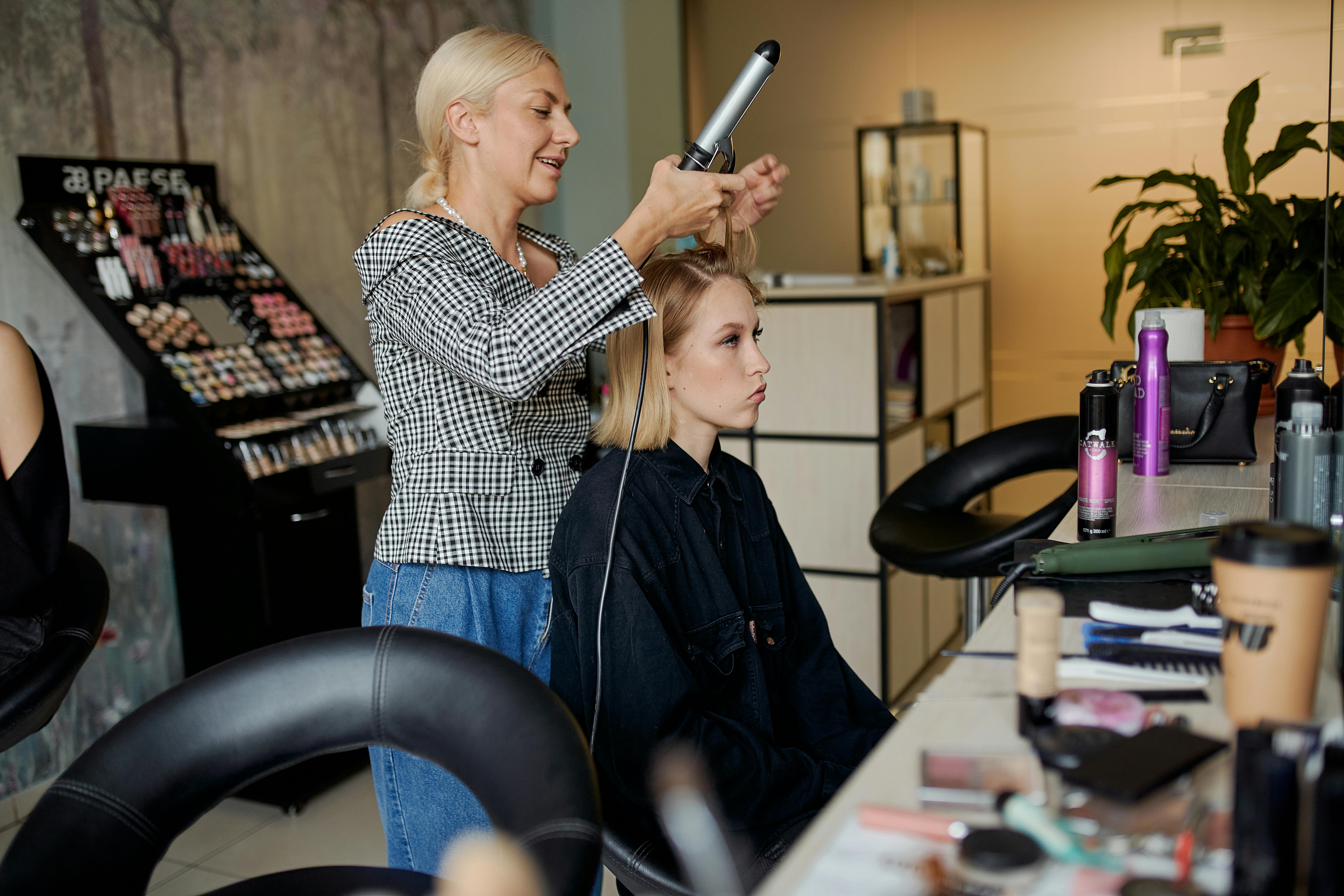 Una peluquera alisando el pelo de una clienta | Fuente: Pexels