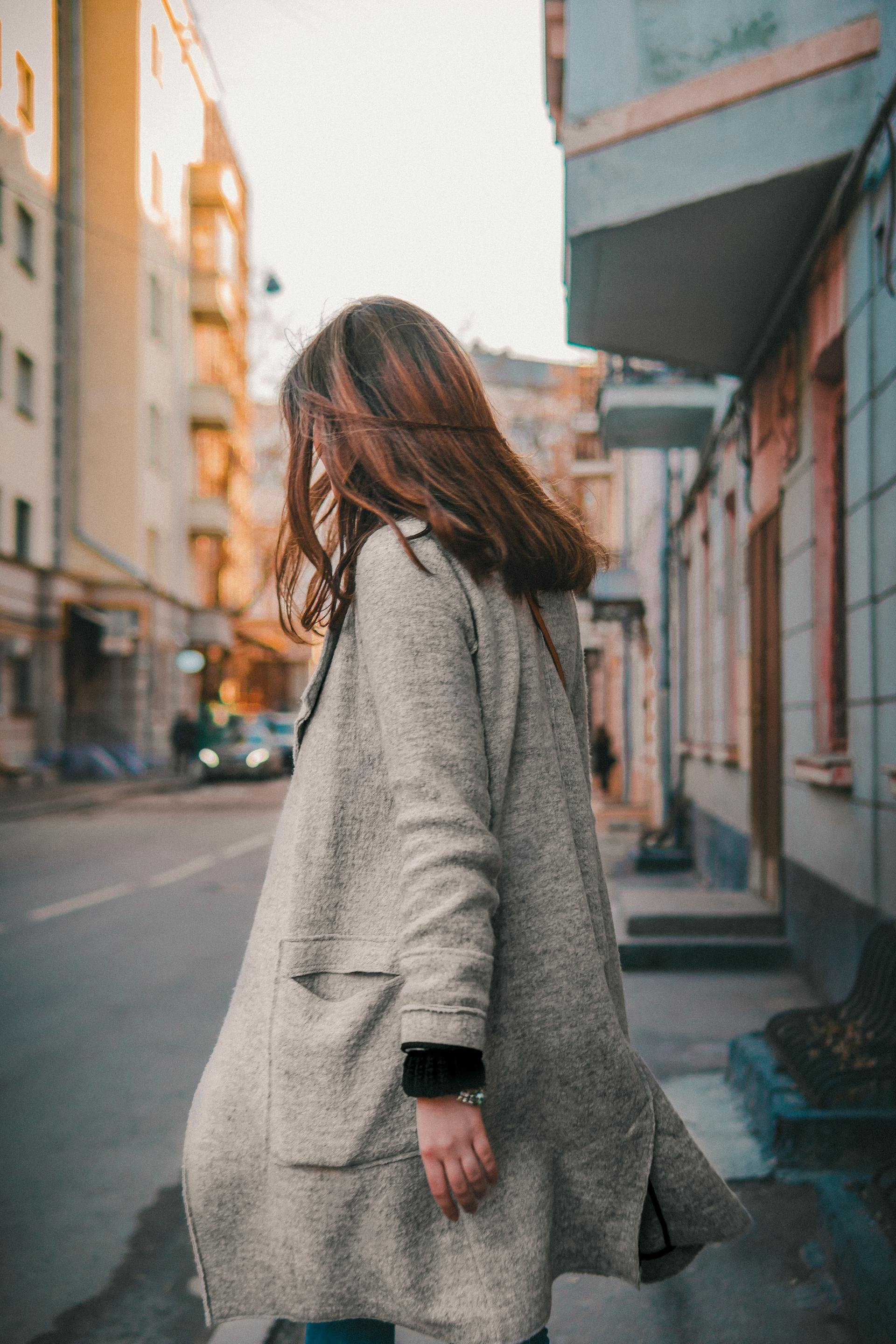 Una mujer con un abrigo gris alejándose | Fuente: Pexels