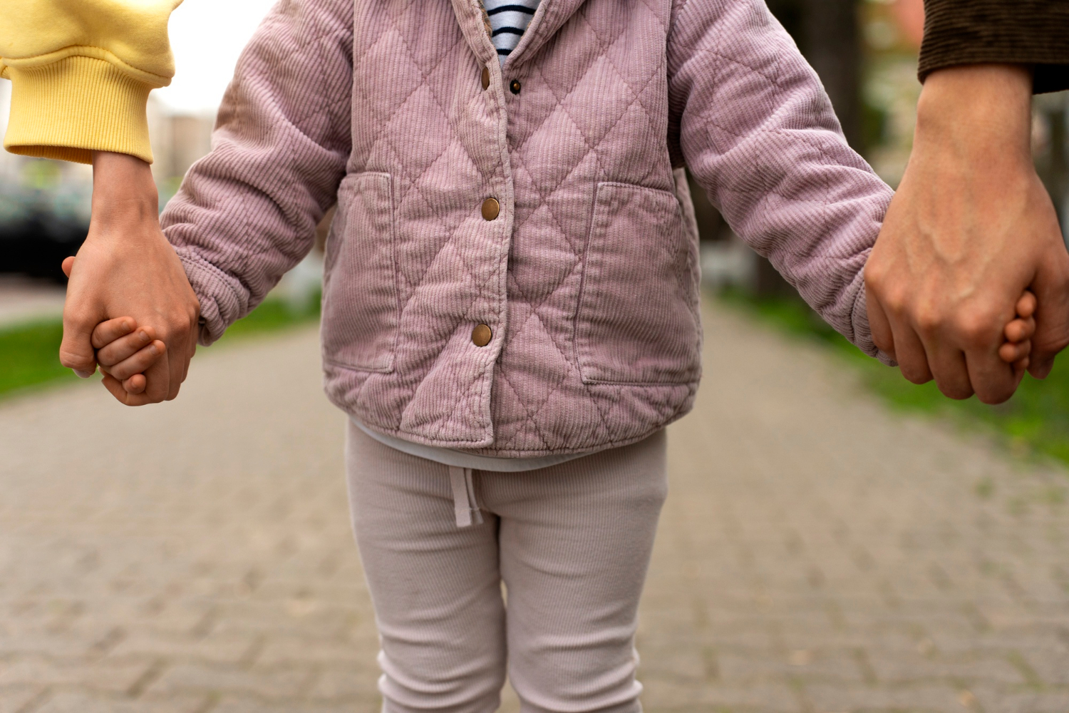 Un niña de la mano de sus padres | Fuente: Freepik