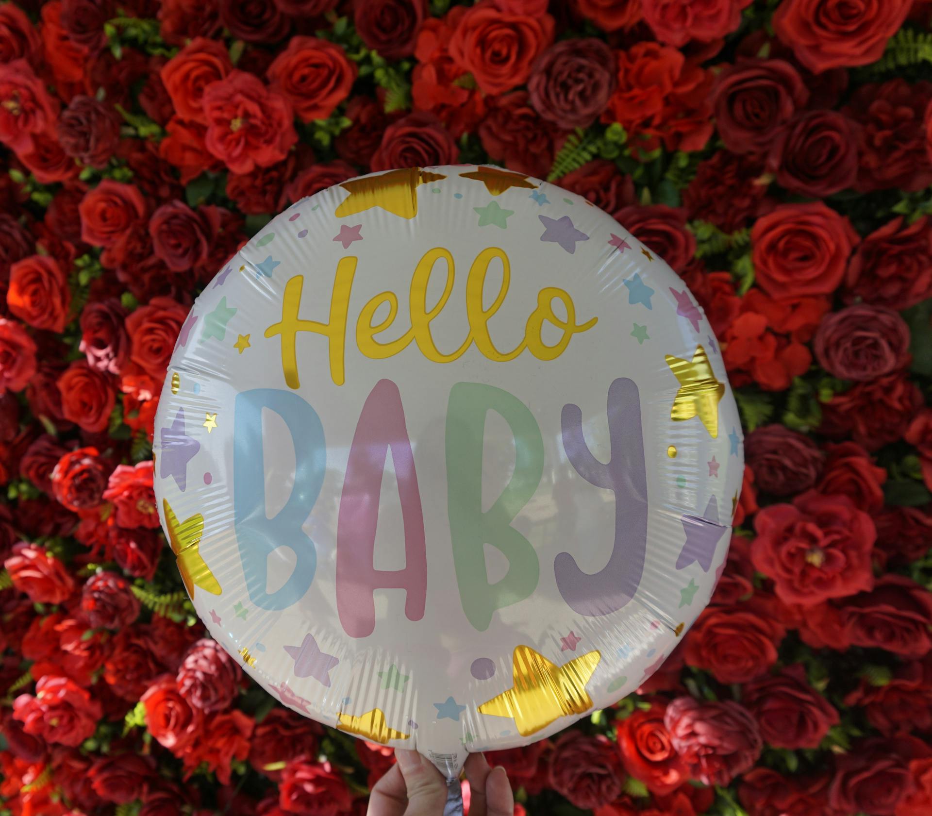 Una persona sostiene un globo con rosas rojas de fondo | Fuente: Pexels
