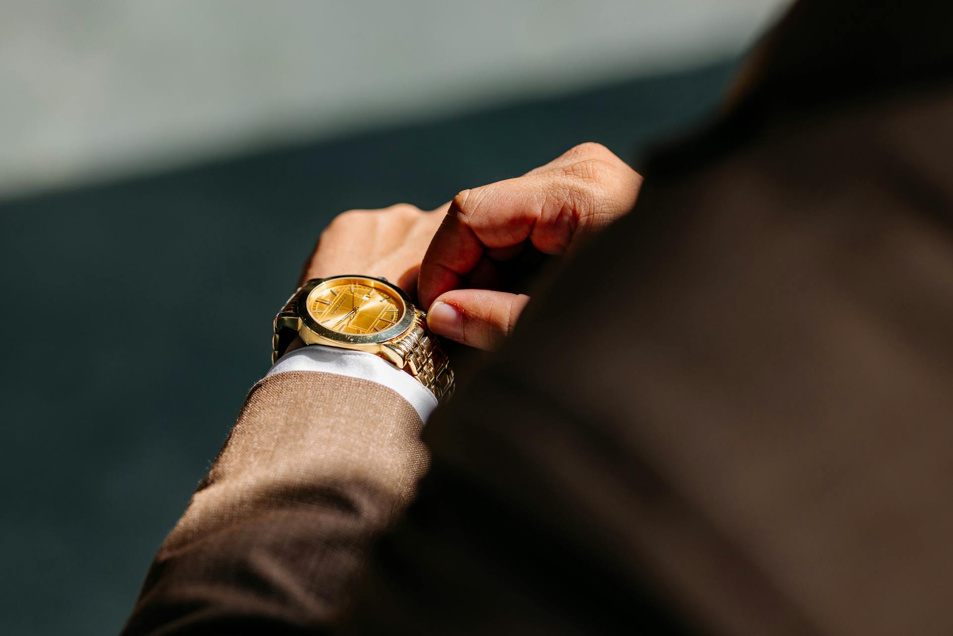 Primer plano de un hombre trajeado tocando su reloj de pulsera | Fuente: Pexels