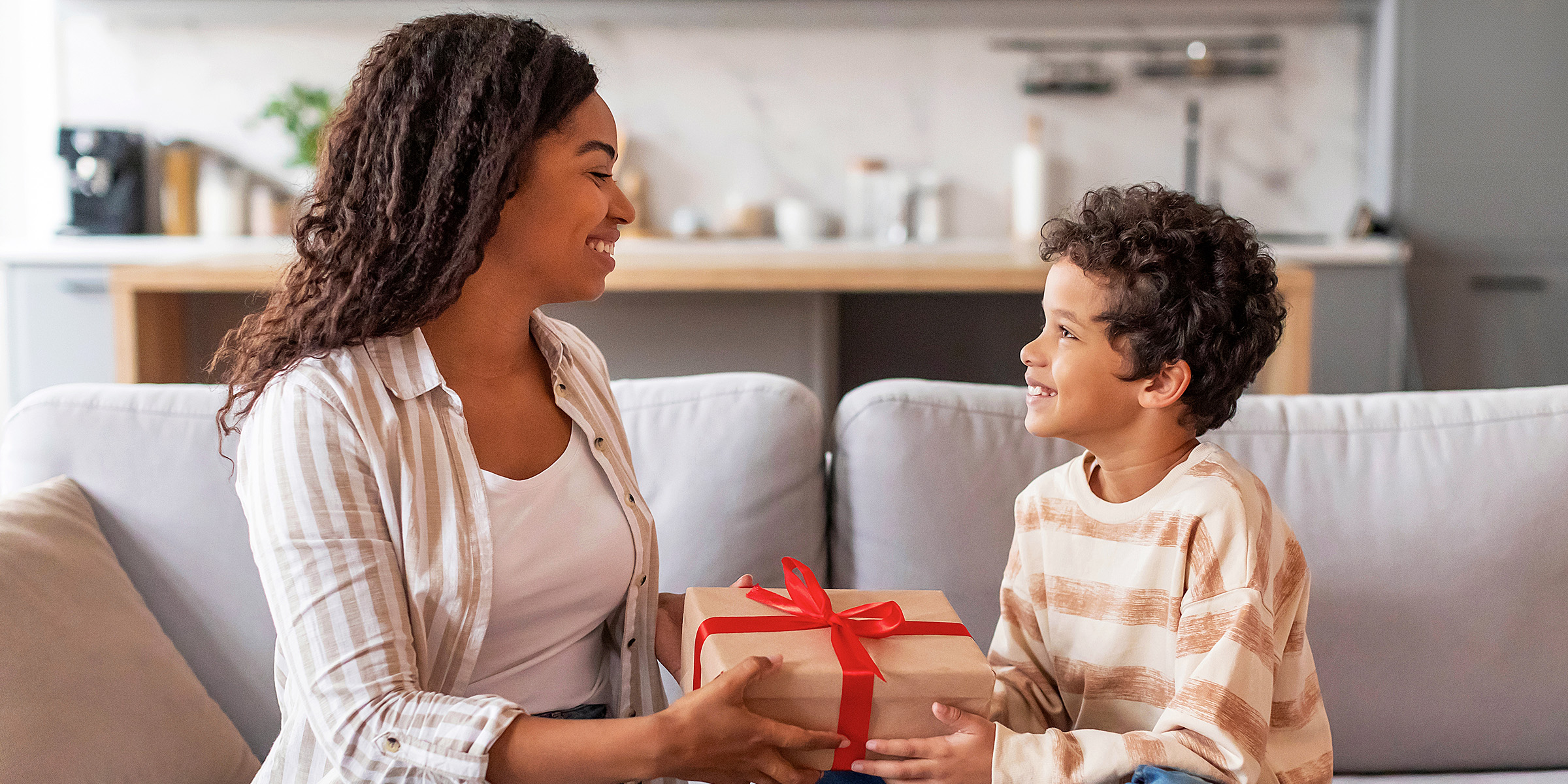 Una mujer dando un regalo a un niño | Fuente: Shutterstock