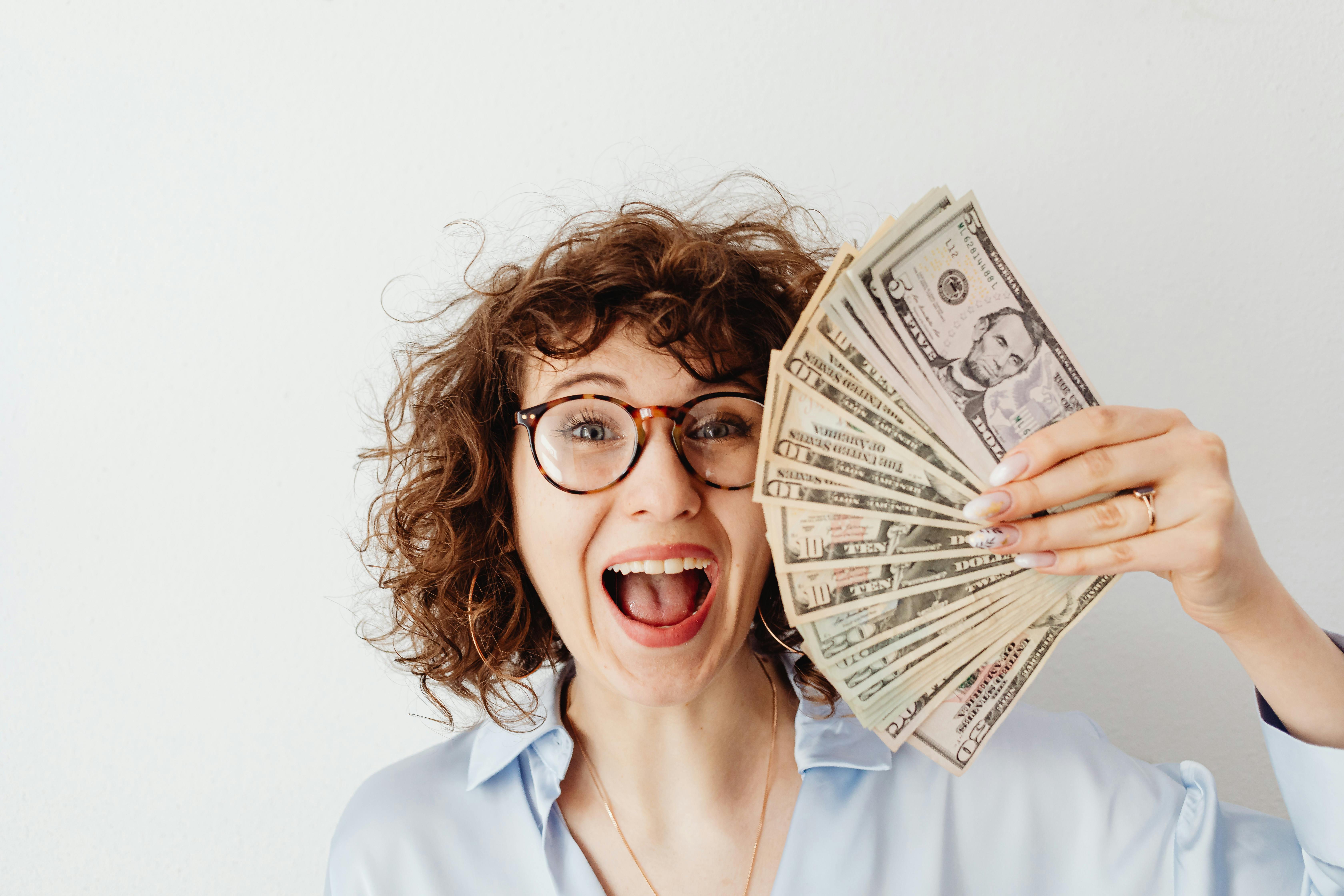Una mujer feliz sosteniendo dinero | Fuente: Pexels