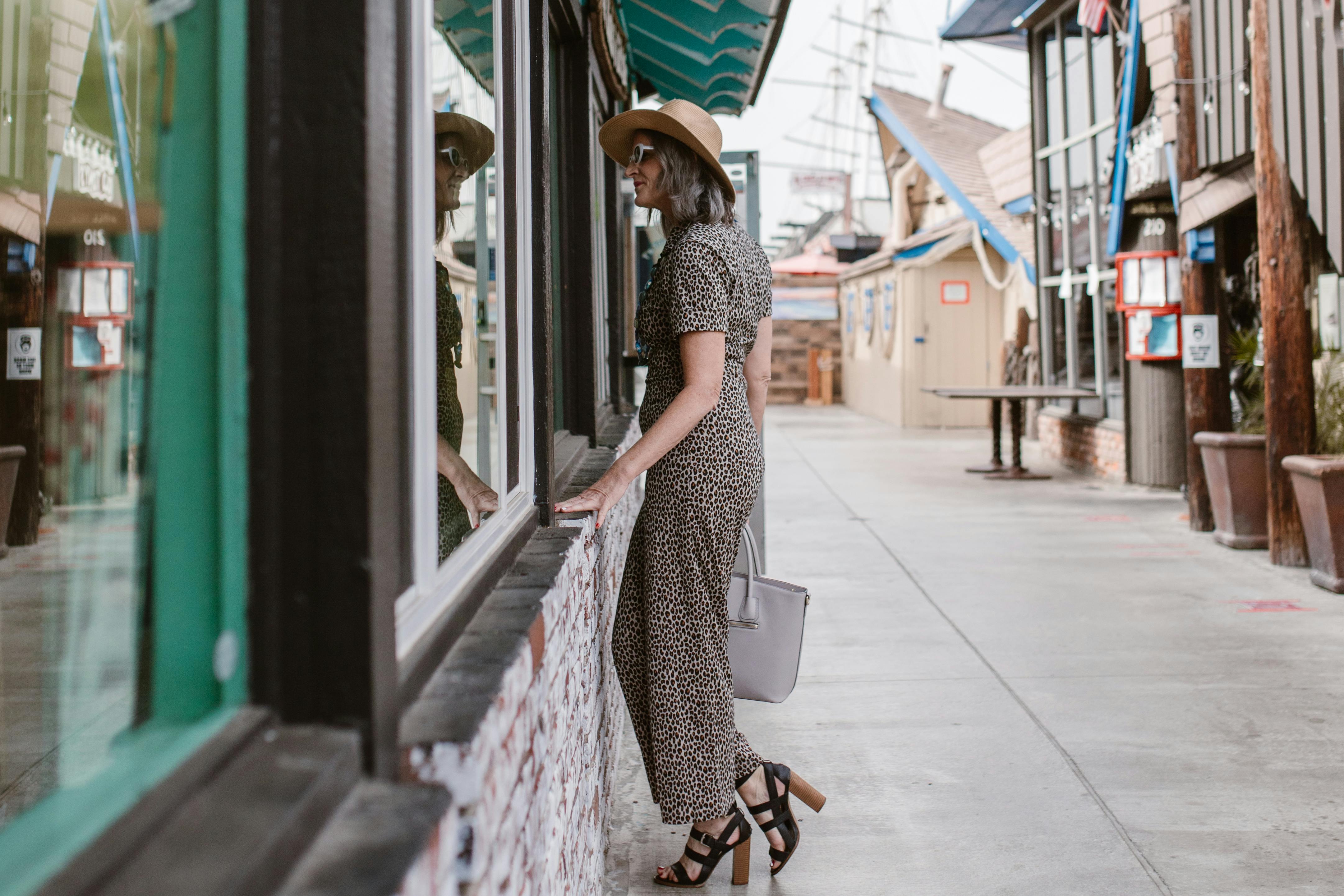 Mujer de pie frente a una tienda, mirando a través de la vidriera | Fuente: Pexels