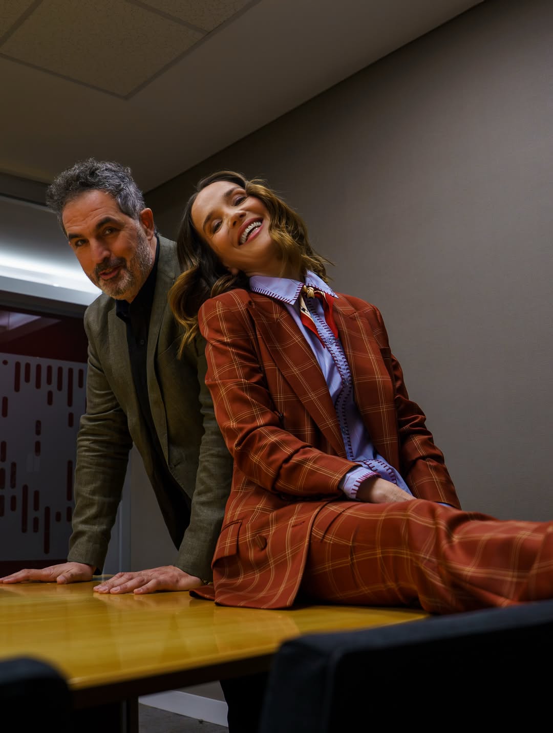 Natalia Oreiro y Juan Taratuto posan durante una actividad promocional de “Nada entre los dos”. La actriz aparece sentada sobre una mesa con su traje de cuadros rojizos y camisa celeste, mientras el director la acompaña con saco verde oliva y camisa negra. | Fuente: Instagram/nataliaoreirosoy