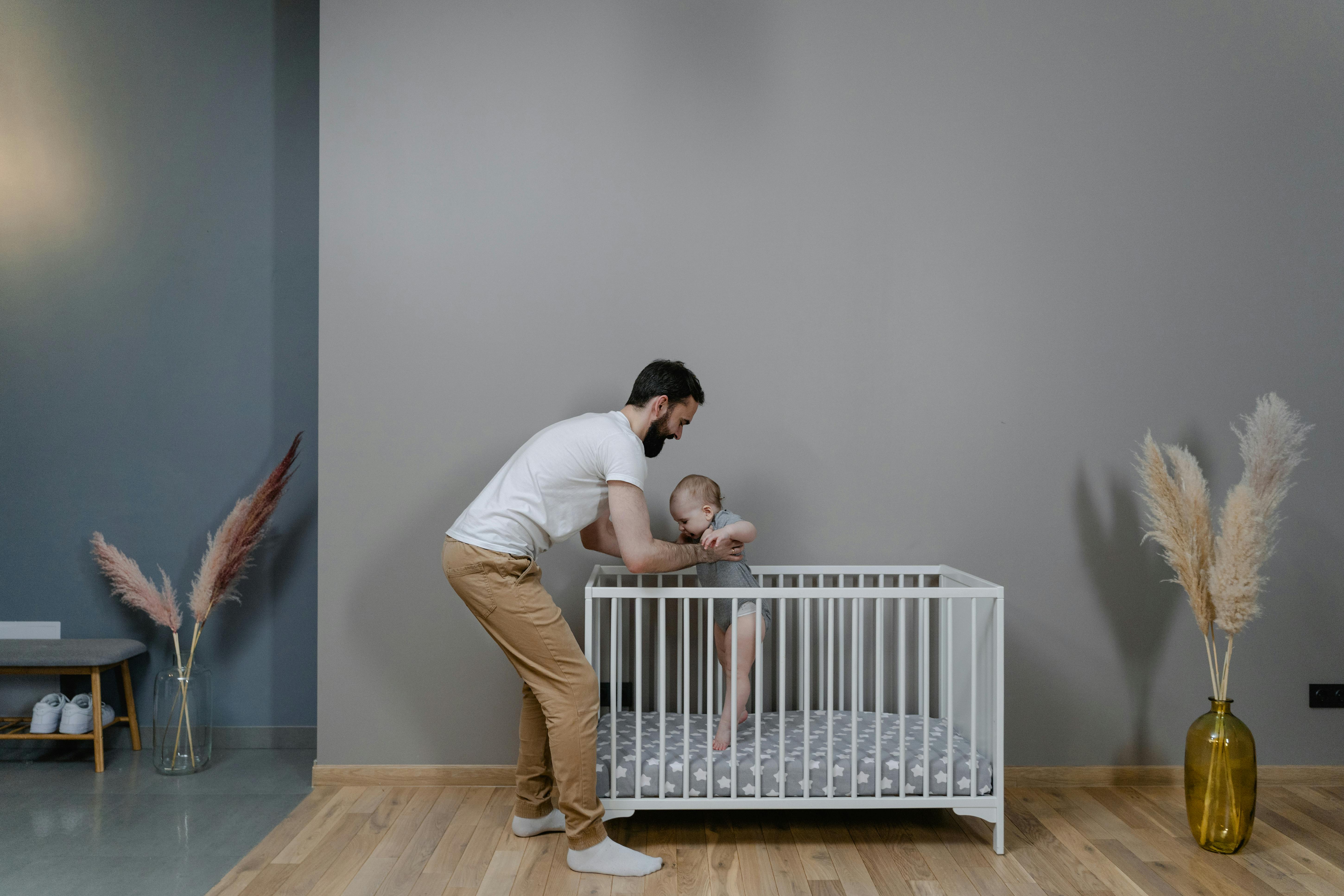 Un hombre sostiene a un bebé en una cuna | Fuente: Pexels