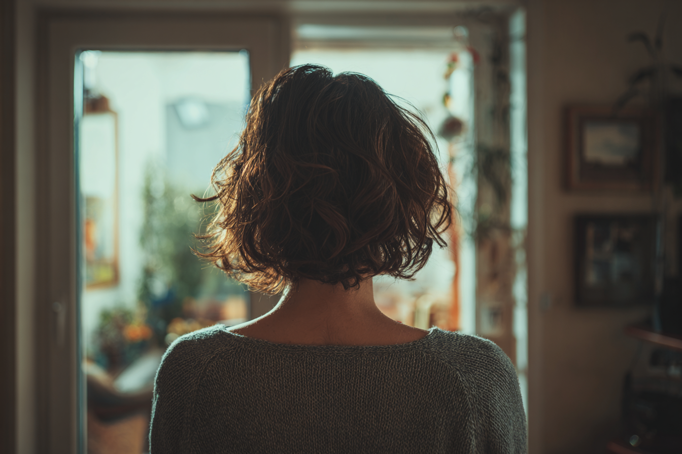 Una mujer de pie en su casa | Fuente: Midjourney
