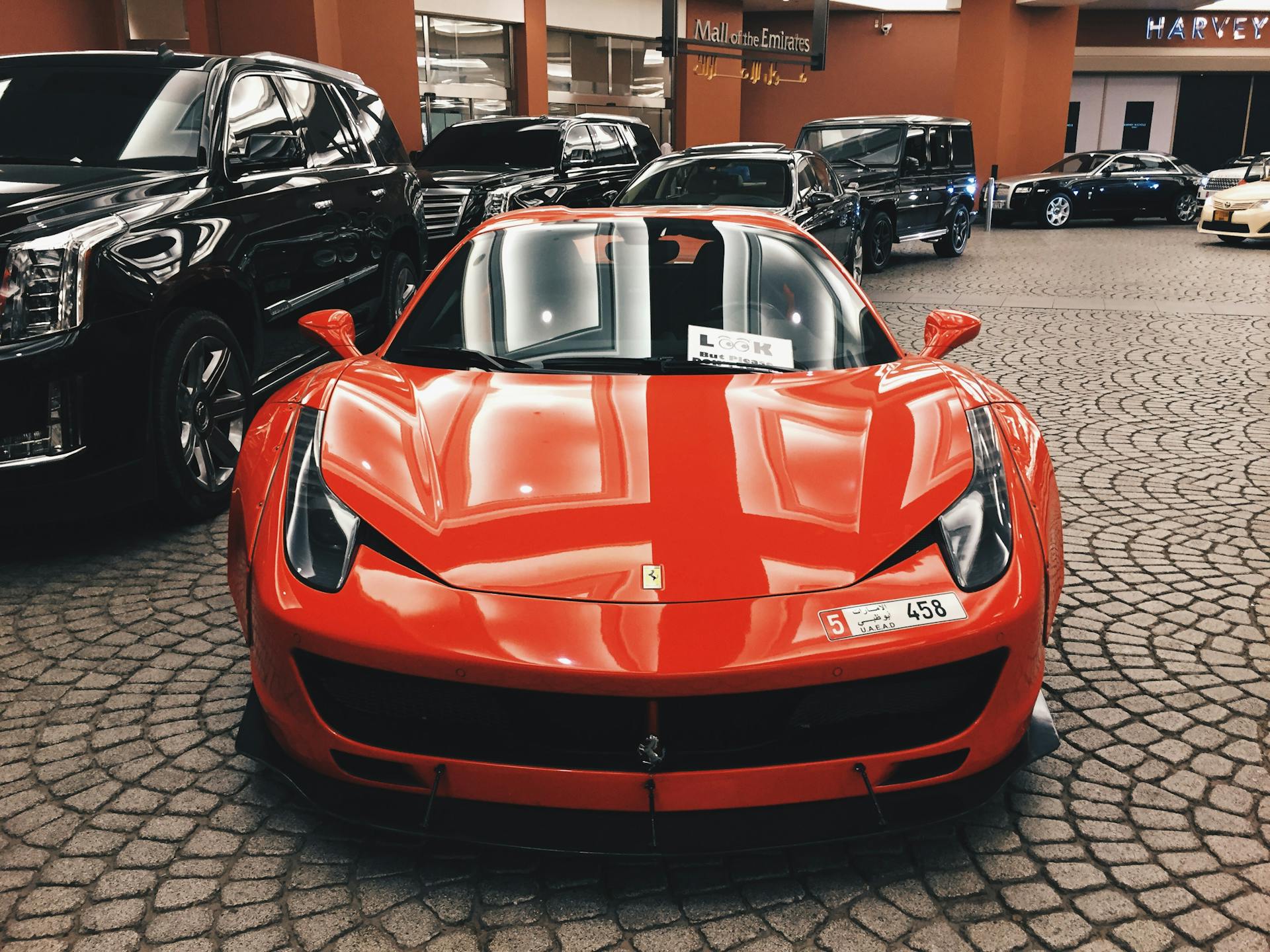 Vista frontal de un Automóvil rojo aparcado en un solar con otros coches al fondo | Fuente: Pexels