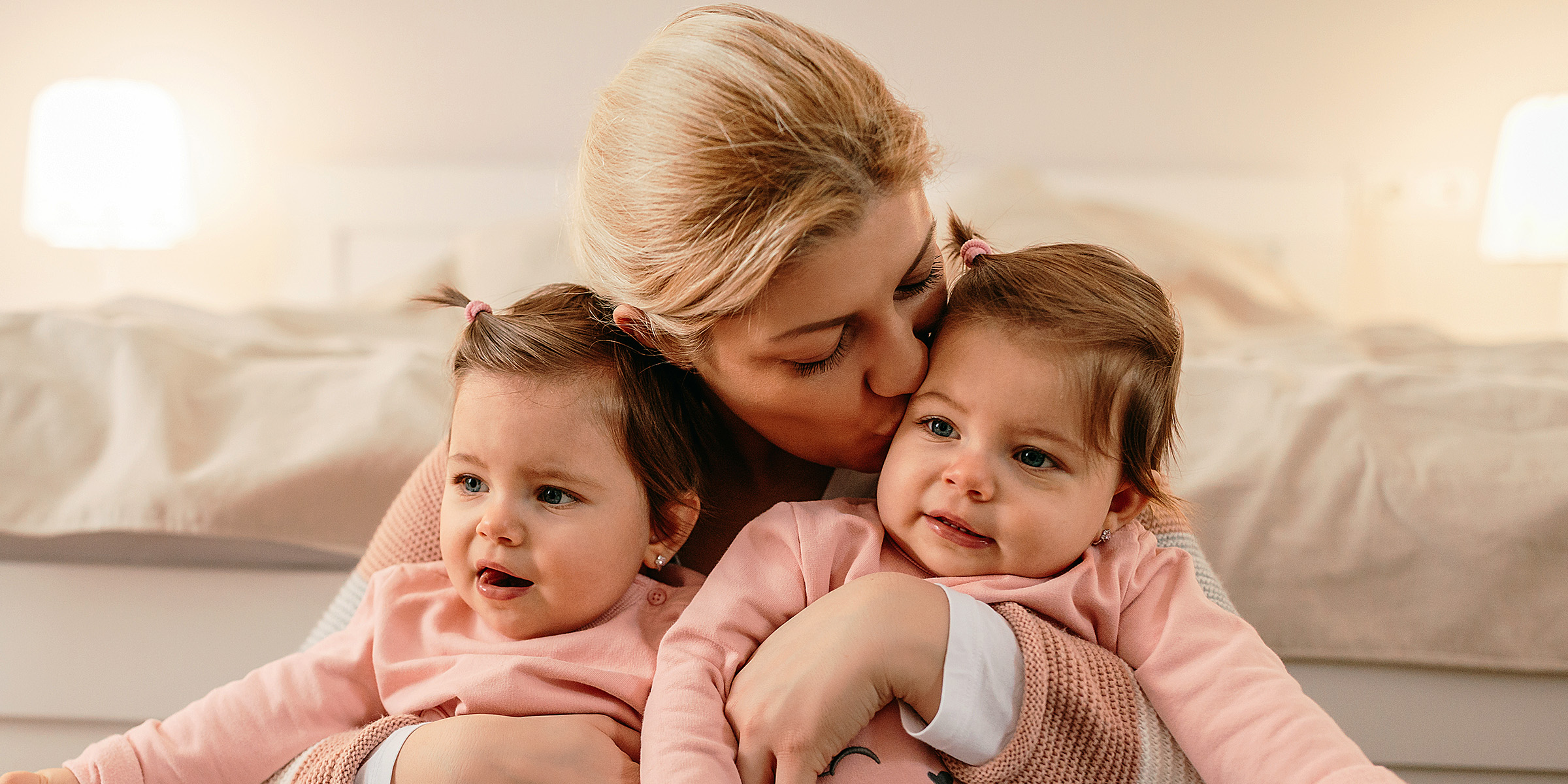 Una mujer con sus hijas gemelas en brazos | Fuente: Shutterstock