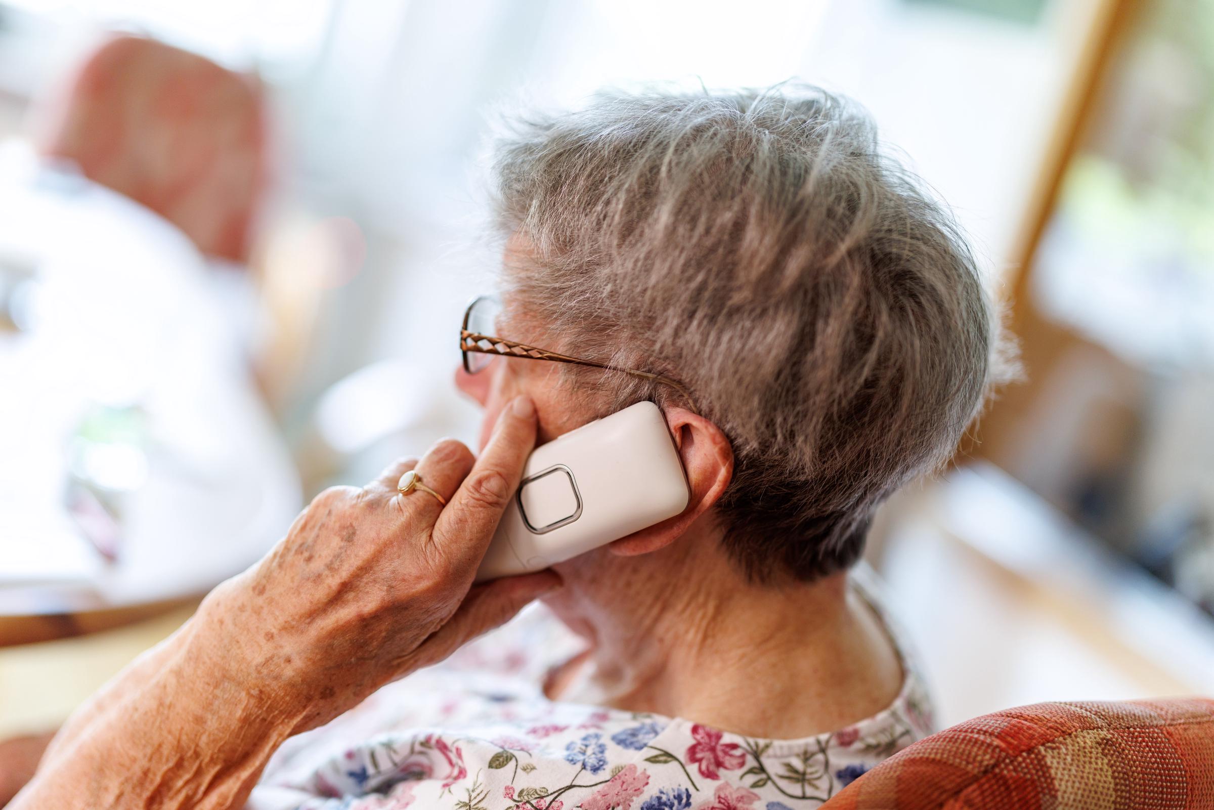 Una mujer mayor haciendo una llamada telefónica con un teléfono inalámbrico en la mano. | Fuente: Getty Images