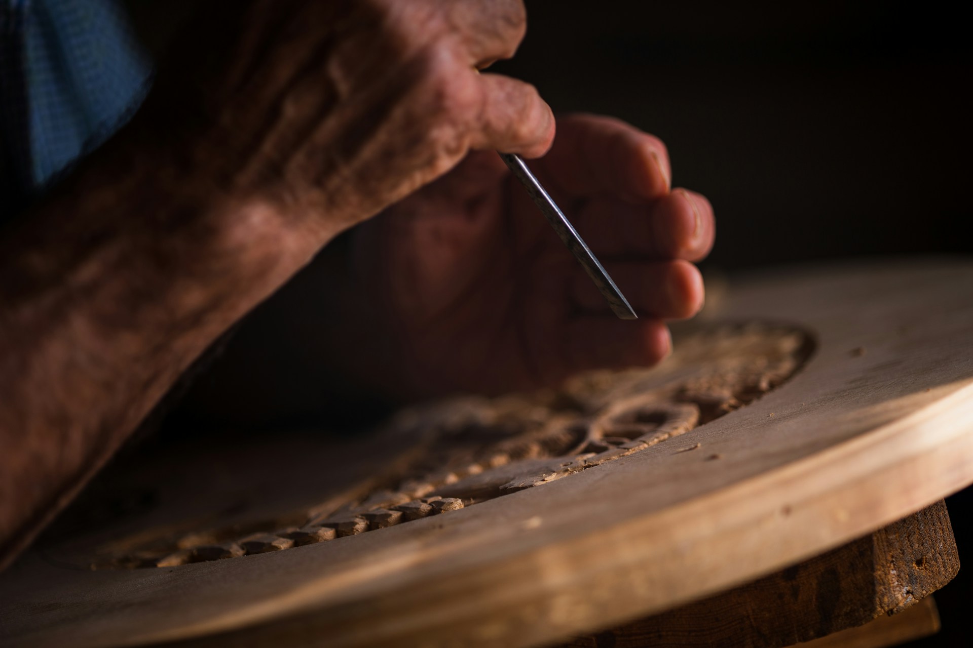 Un hombre tallando un diseño en un trozo de madera | Fuente: Unsplash