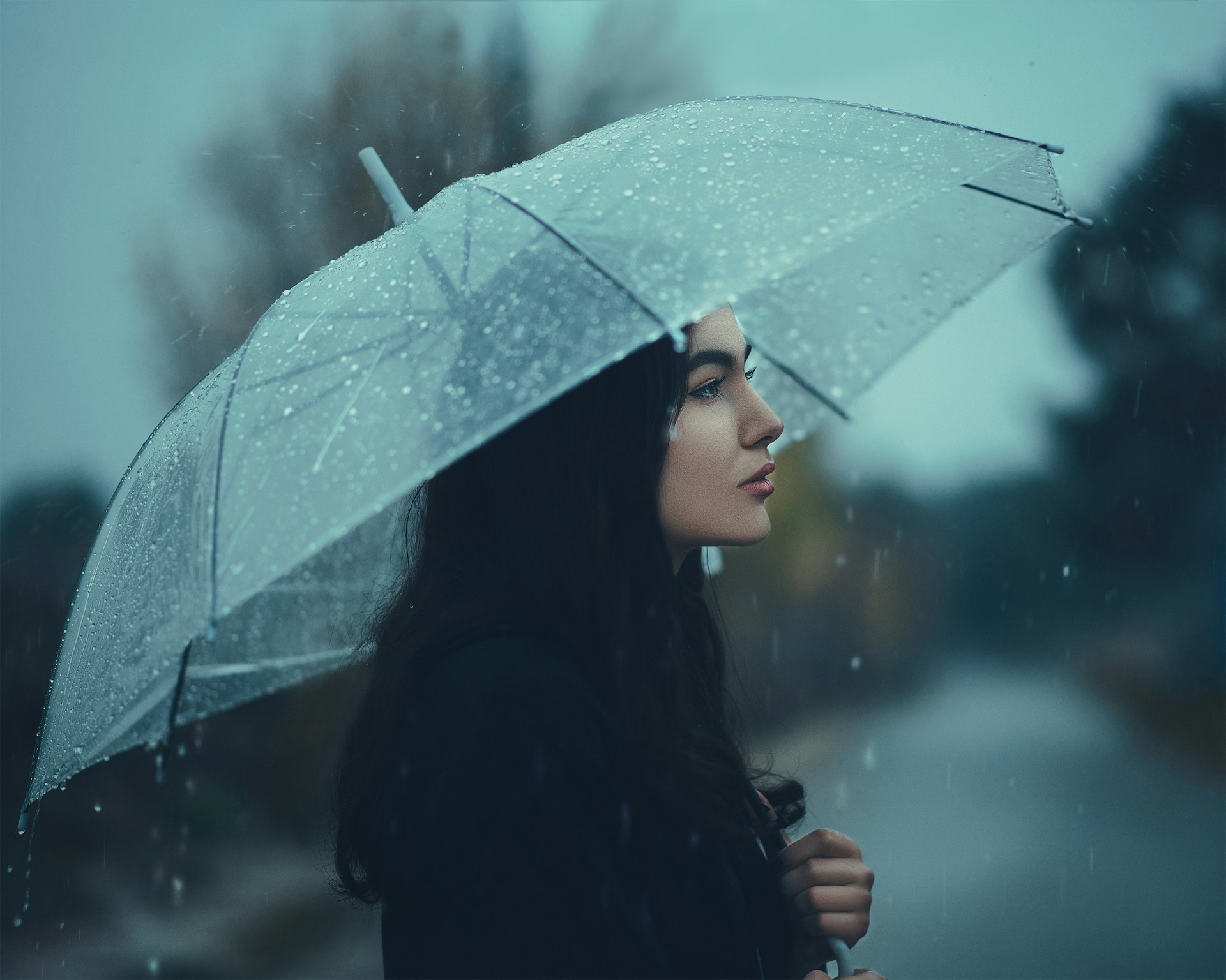 Una mujer de pie bajo la lluvia con un paraguas | Fuente: Unsplash