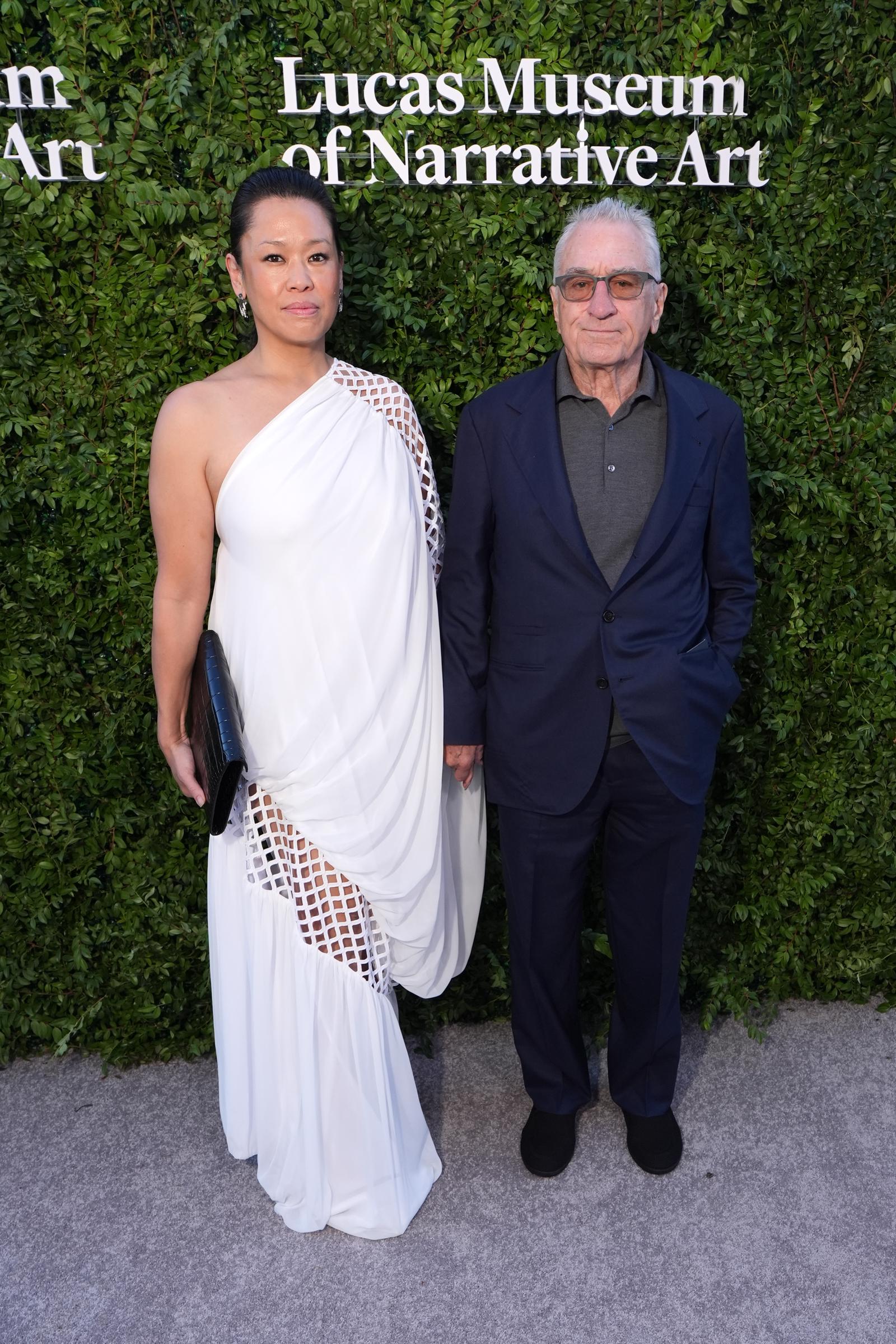 El vaporoso vestido blanco de Tiffany Chen destacaba junto al conjunto más oscuro de Robert De Niro mientras posaban juntos. Su aparición aportó otro toque distintivo a la velada. | Fuente: Getty Images