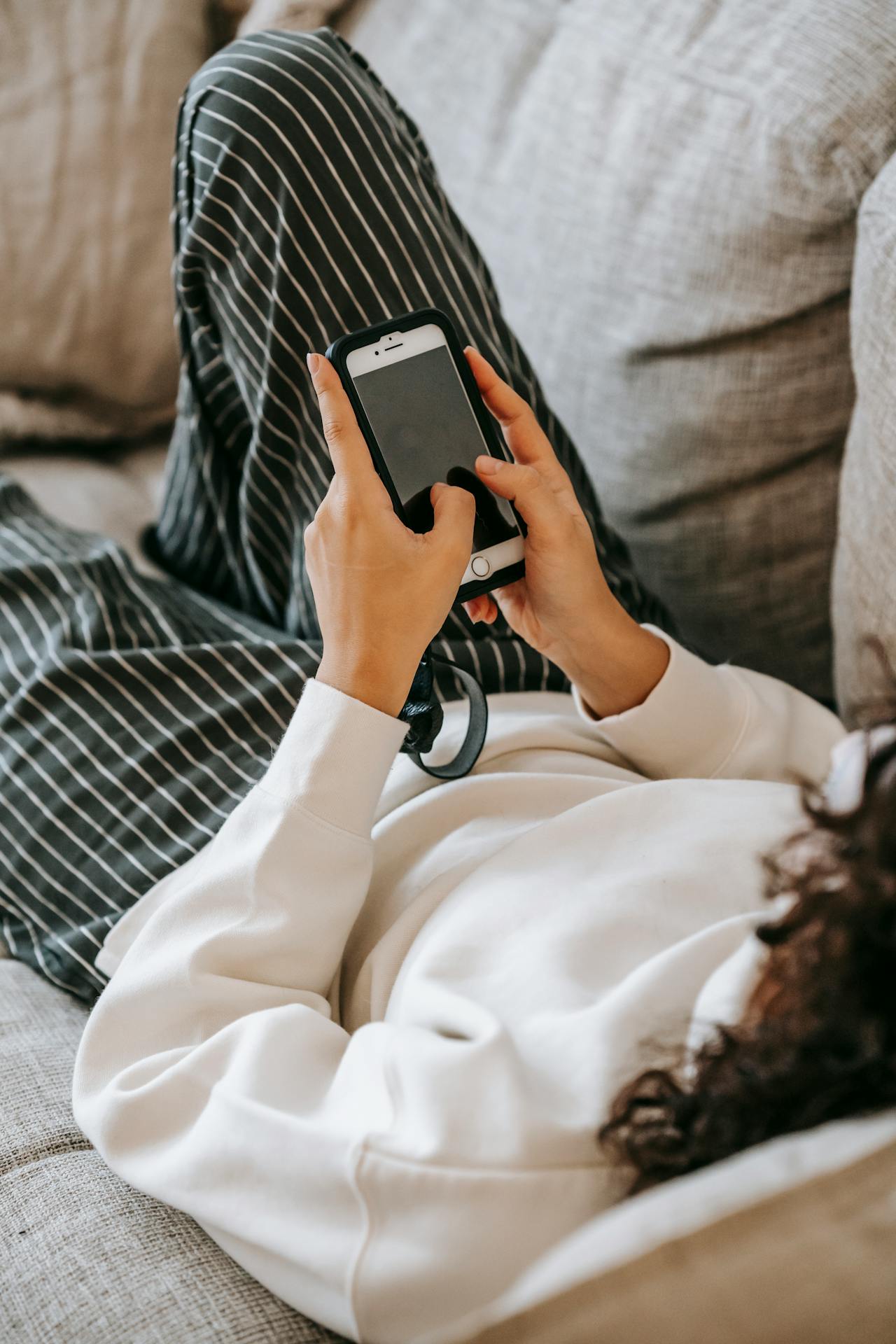 Una mujer descansando en el sofá y utilizando su teléfono | Fuente: Pexels