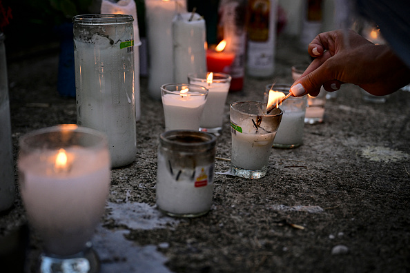 Una mujer enciende una vela mientras amigos y familiares rinden homenaje a las víctimas frente a la discoteca Jet Set en Santo Domingo, el 11 de abril de 2025 | Fuente: Getty Images