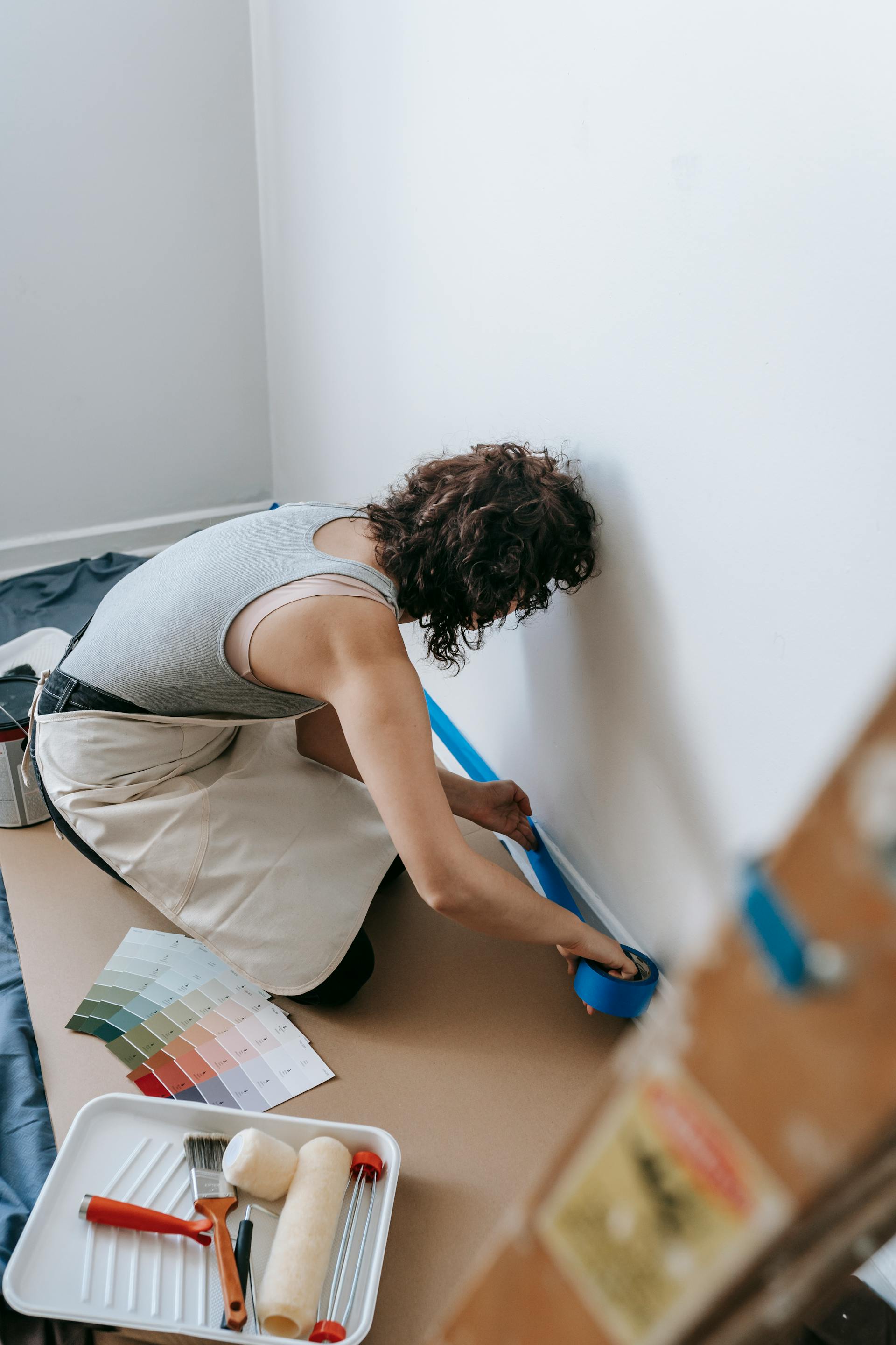 Una mujer se prepara para pintar pegando cinta adhesiva en la pared | Fuente: Pexels