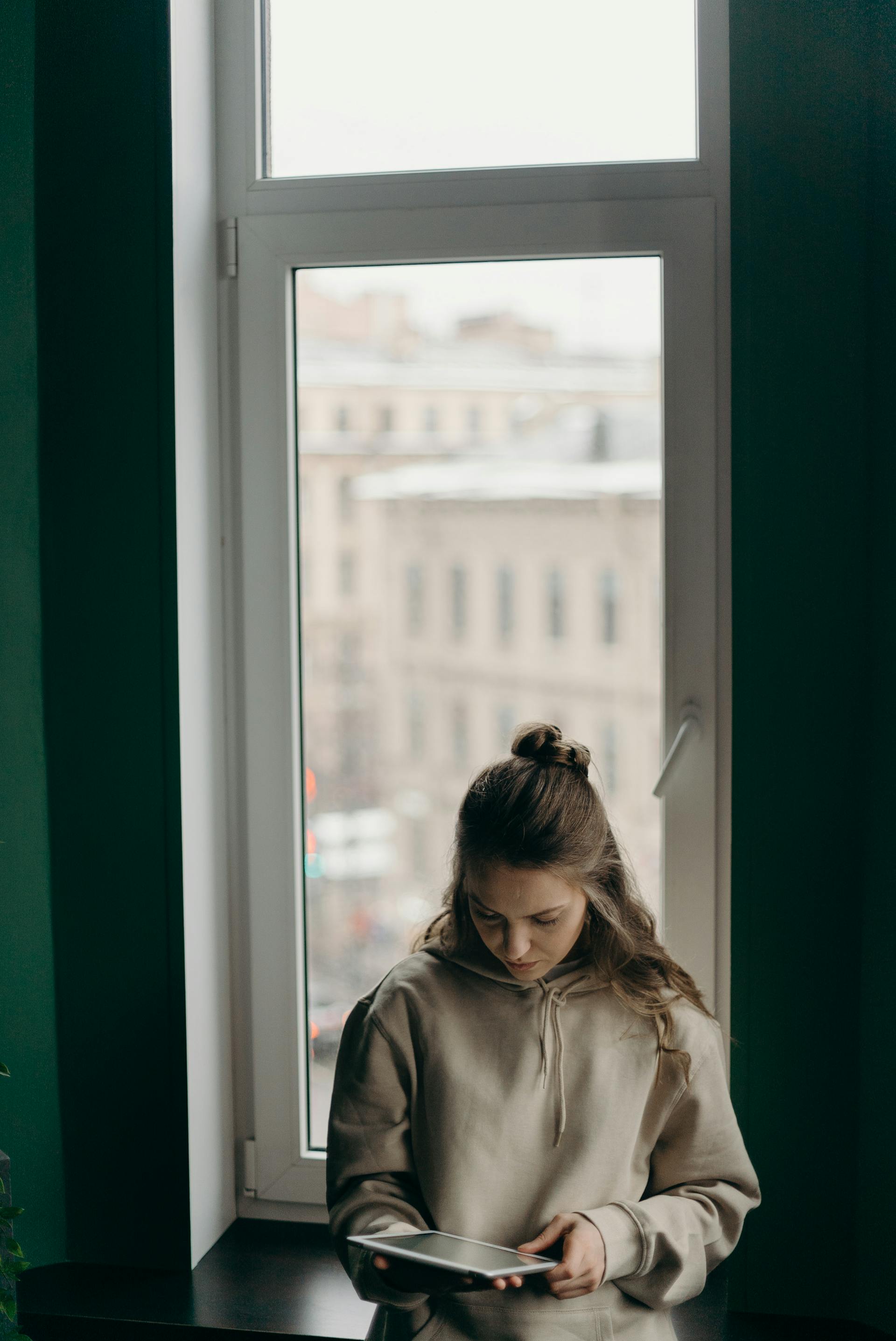 Una mujer mira su iPad de pie cerca de la ventana | Fuente: Pexels