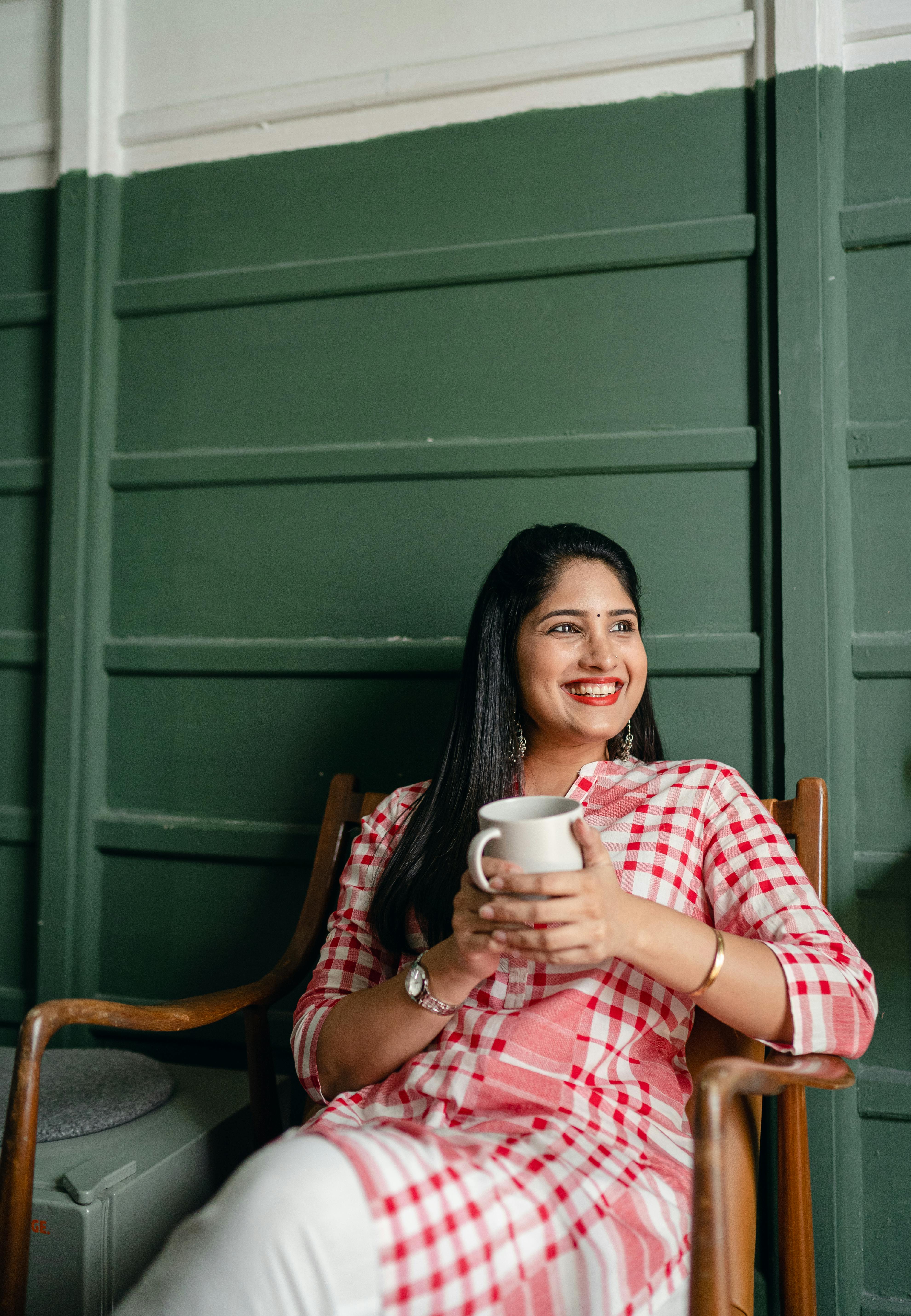Mujer feliz sosteniendo una taza de bebida | Fuente: Pexels