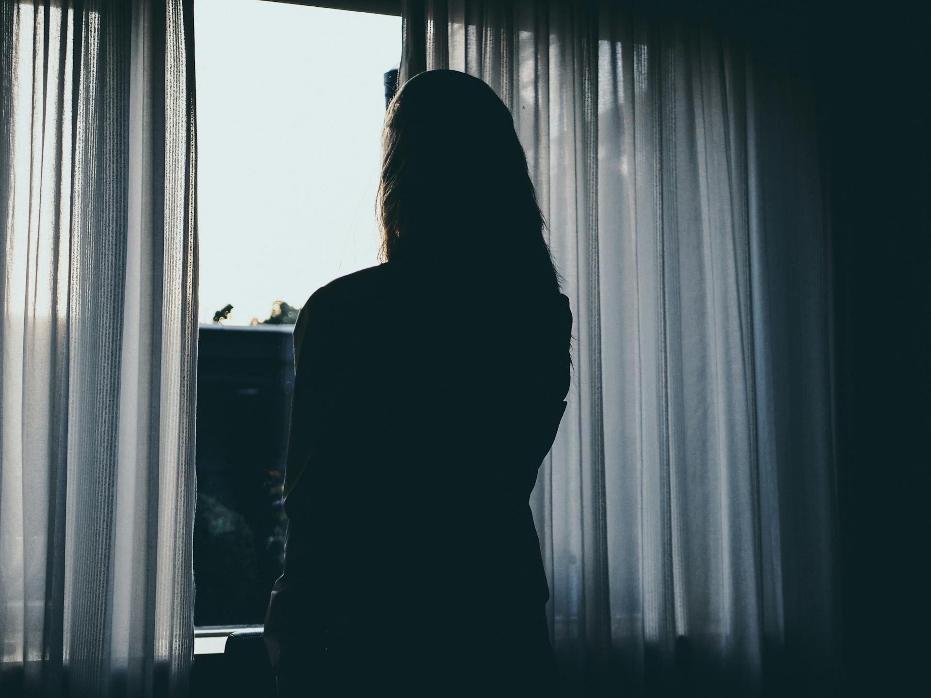 Una mujer de pie cerca de la ventana | Fuente: Pexels