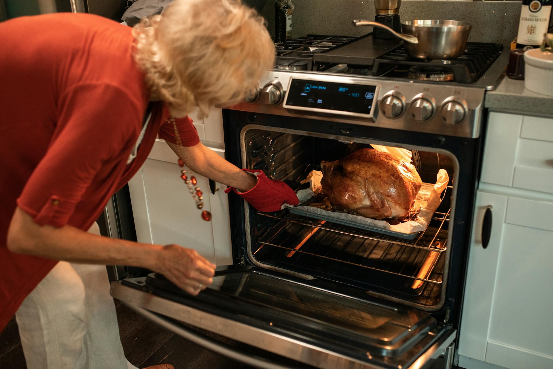 Una mujer mayor colocando una bandeja de pollo asado en el horno | Fuente: Pexels
