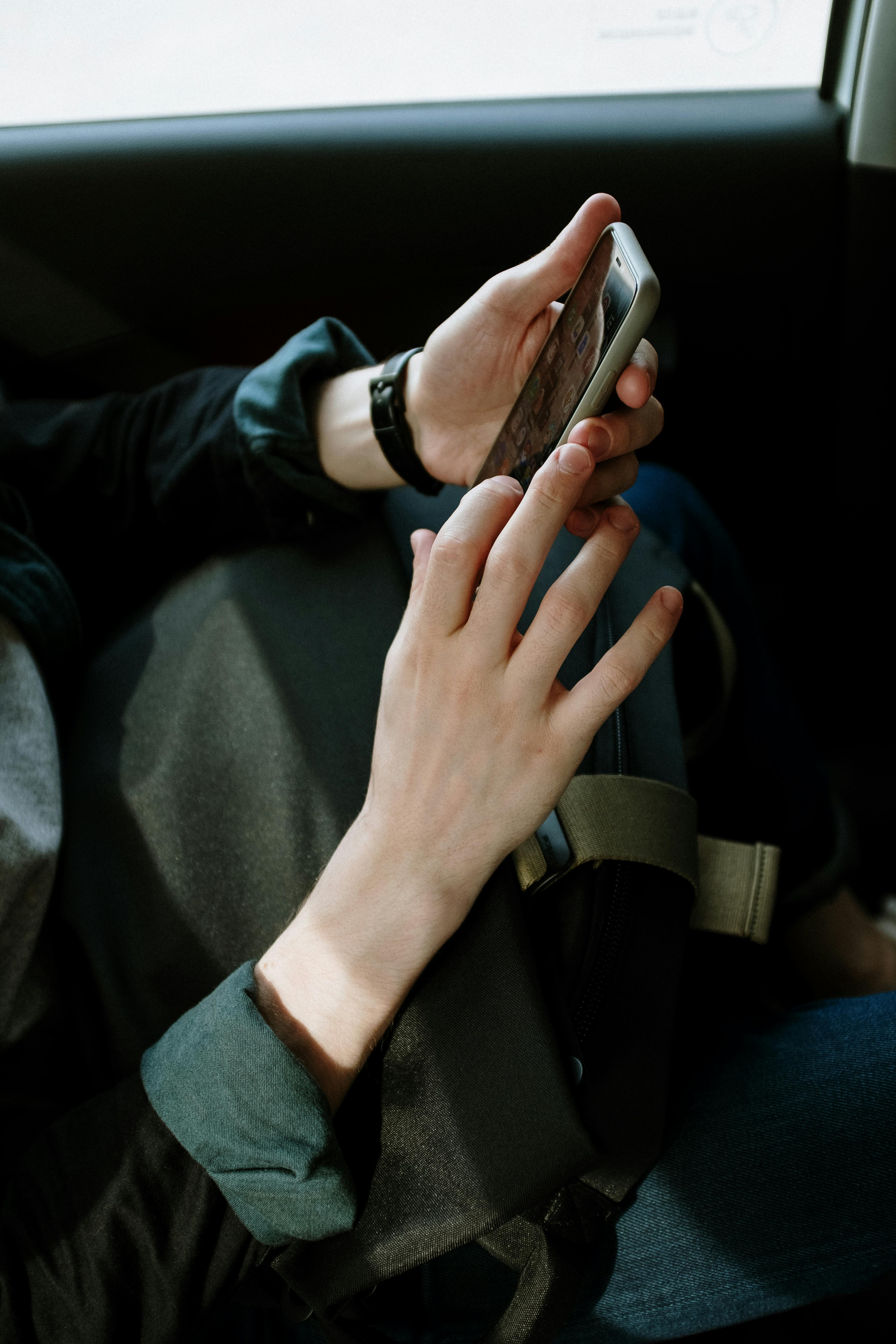 Una persona sostiene un teléfono móvil en un automóvil | Fuente: Pexels