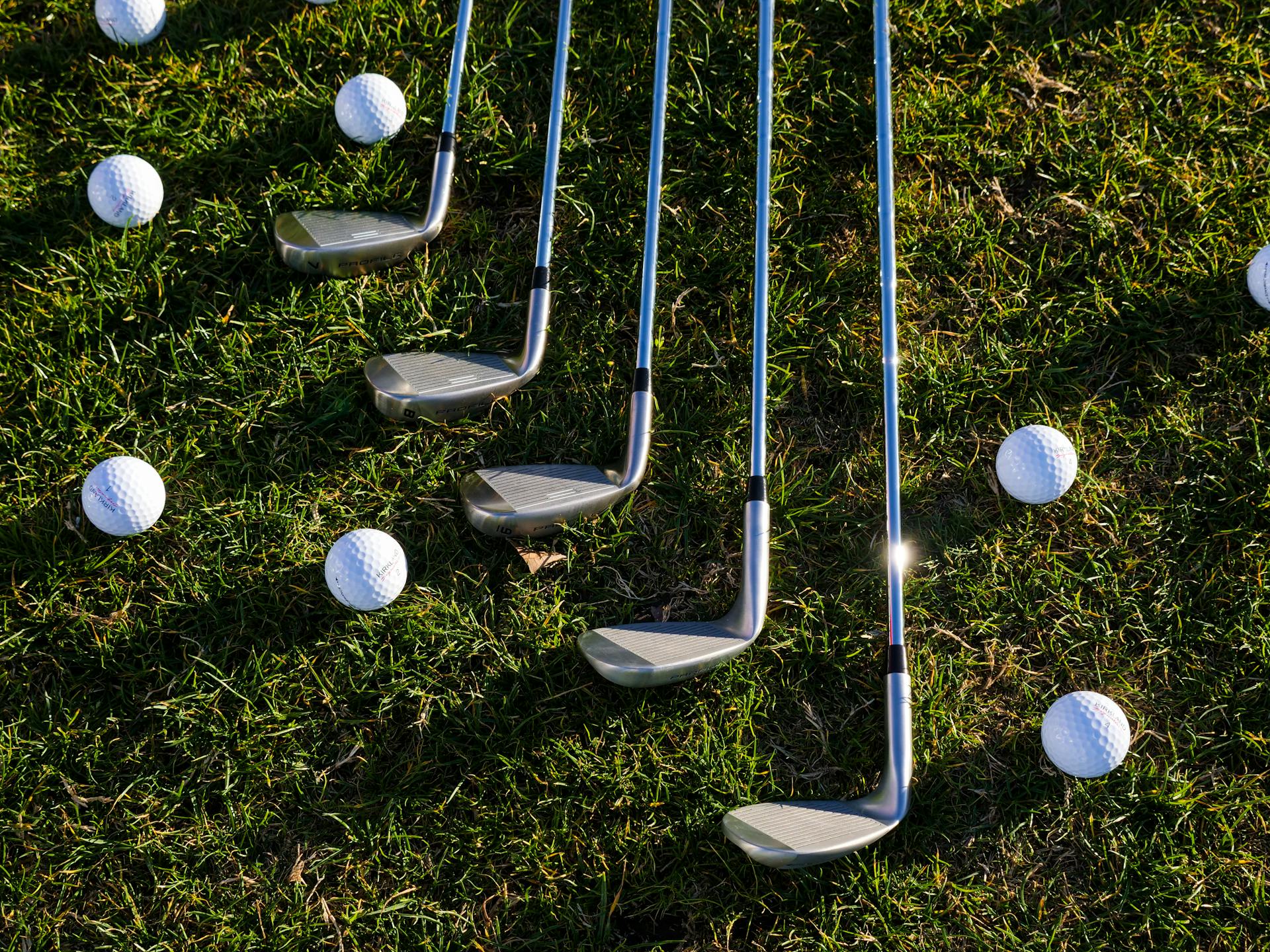 Pelotas y palos de golf tirados en la hierba | Fuente: Pexels