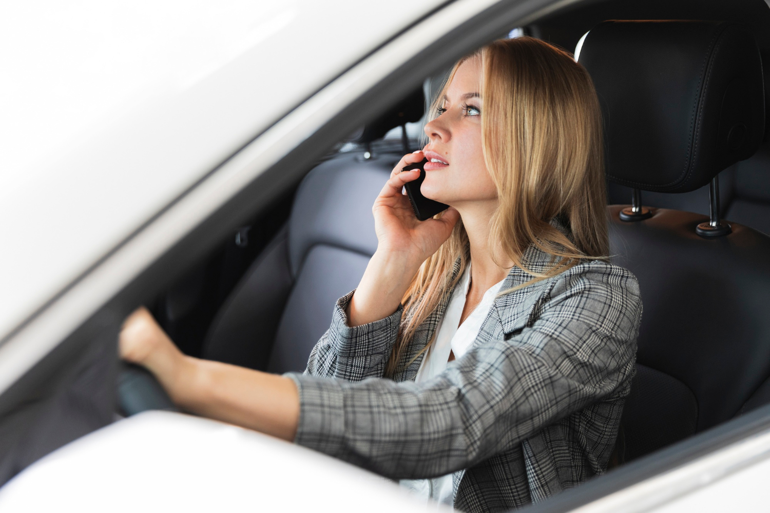 Una mujer sentada en su Automóvil y hablando por teléfono | Fuente: Freepik