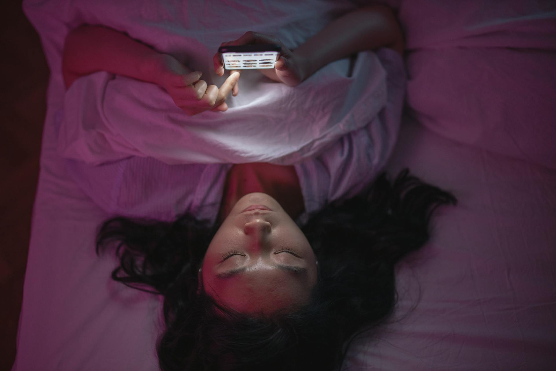 Una mujer mirando el móvil en la cama | Fuente: Pexels