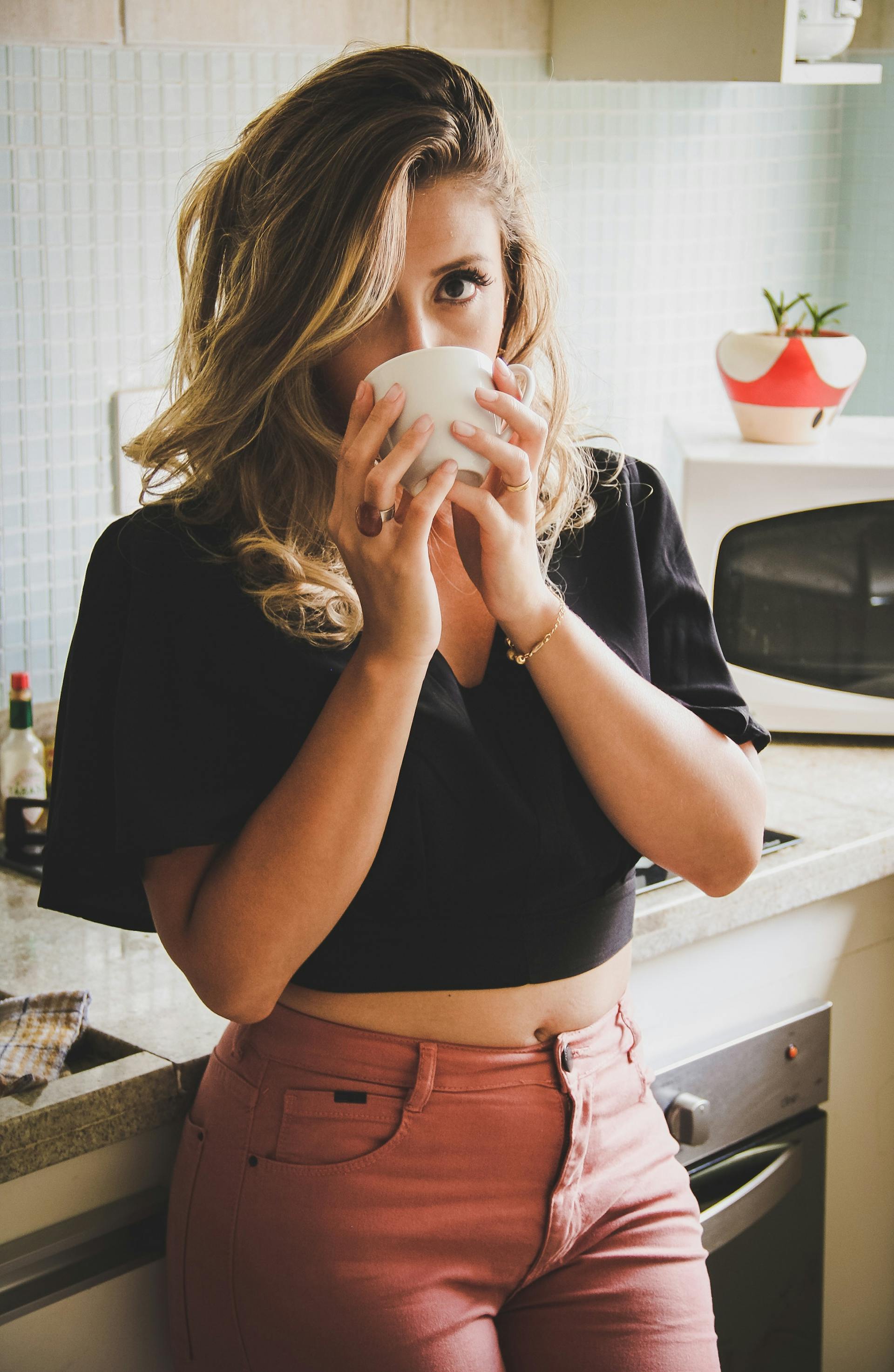 Una mujer tomando café en una cocina | Fuente: Pexels
