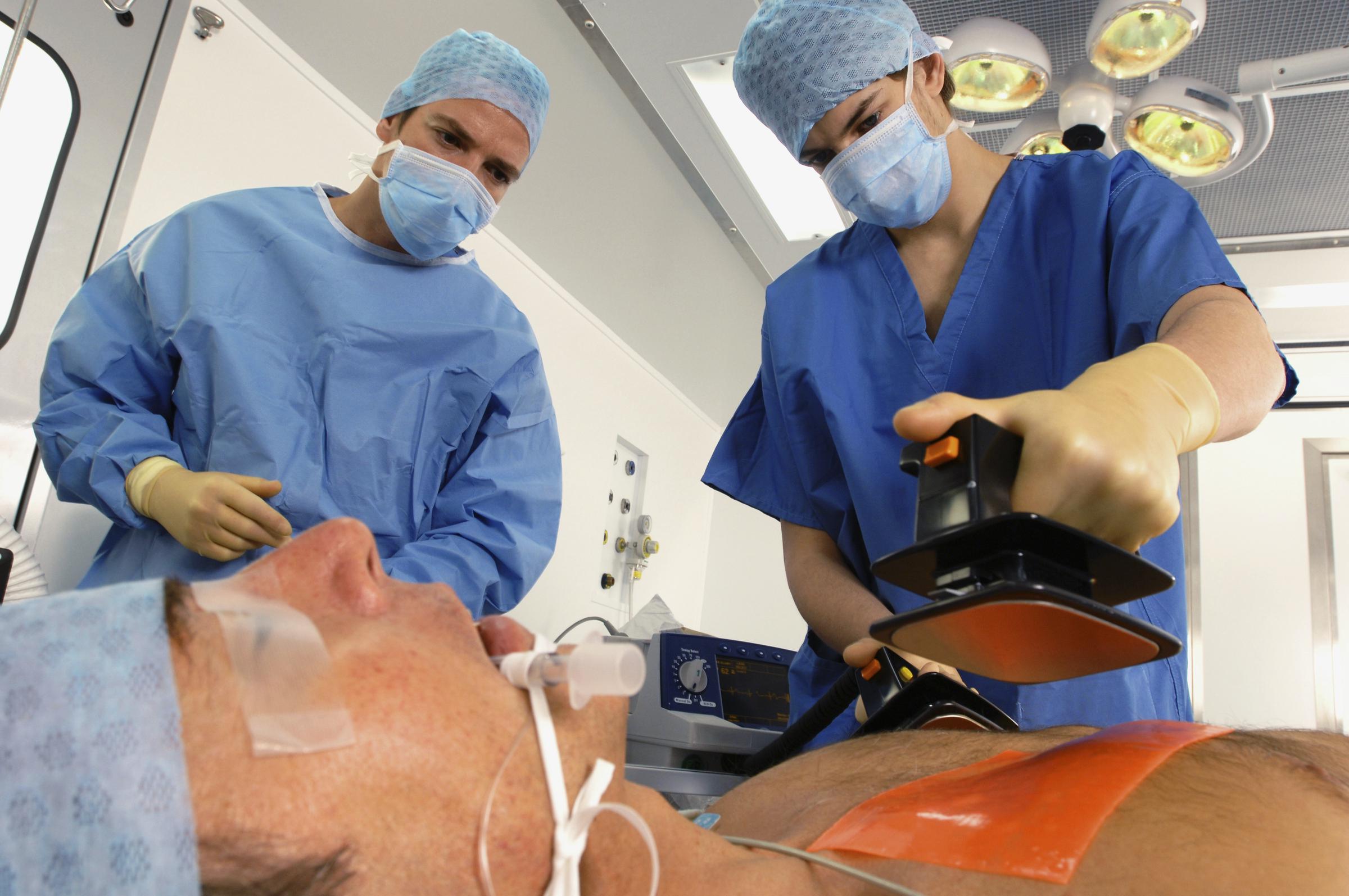 Médicos utilizando un desfibrilador para reanimar a un hombre víctima de un infarto | Fuente: Getty Images