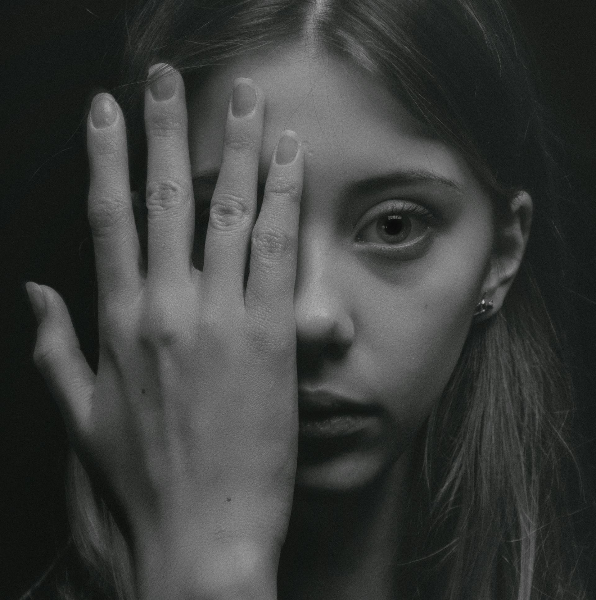 Una foto en escala de grises de una joven cubriéndose la mitad de la cara | Fuente: Pexels