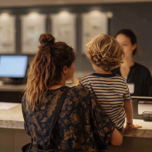 Una mujer y un niño hablando con una recepcionista | Fuente: Midjourney