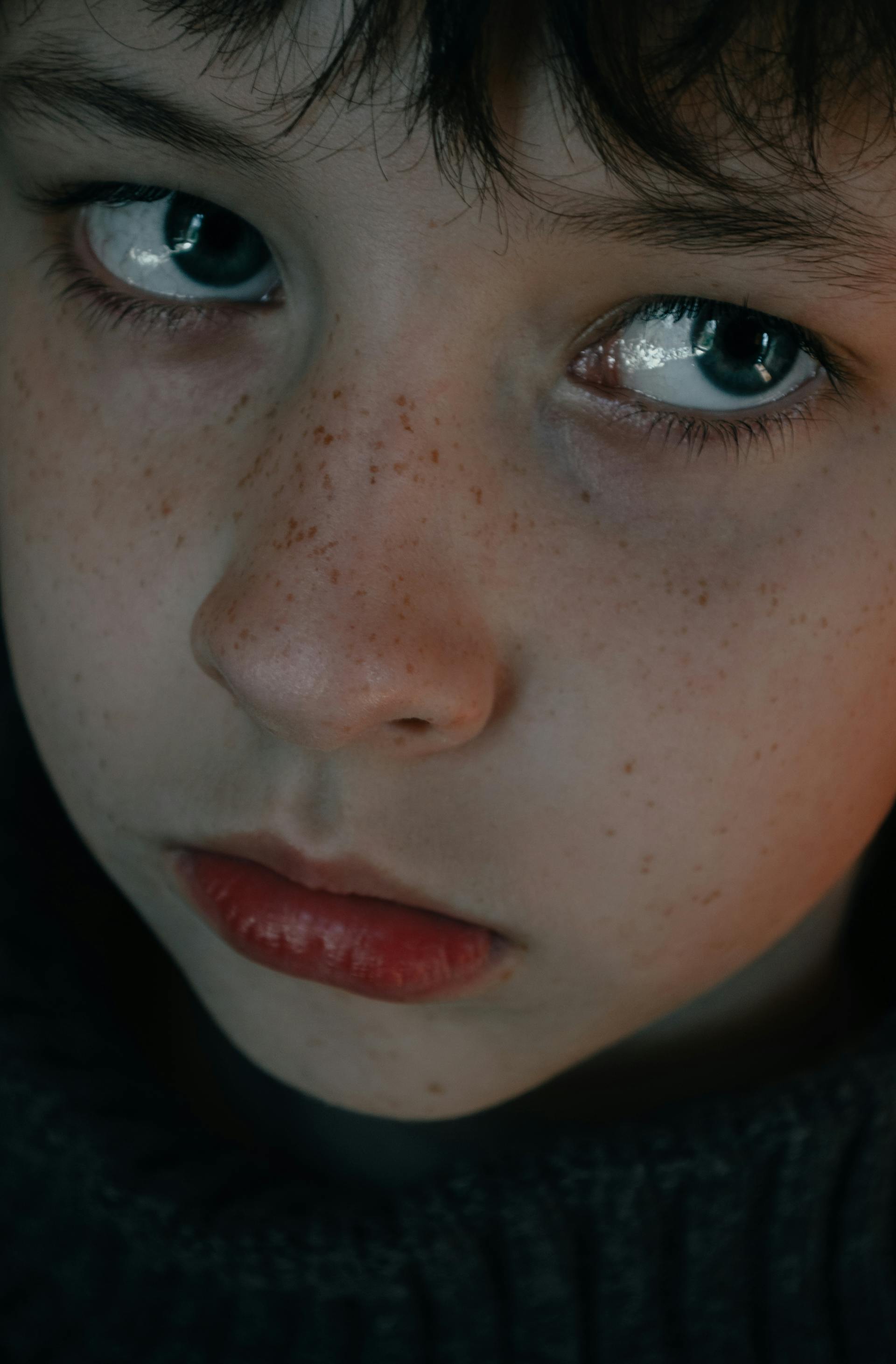 Un niño triste con pecas y ojos azules | Fuente: Pexels