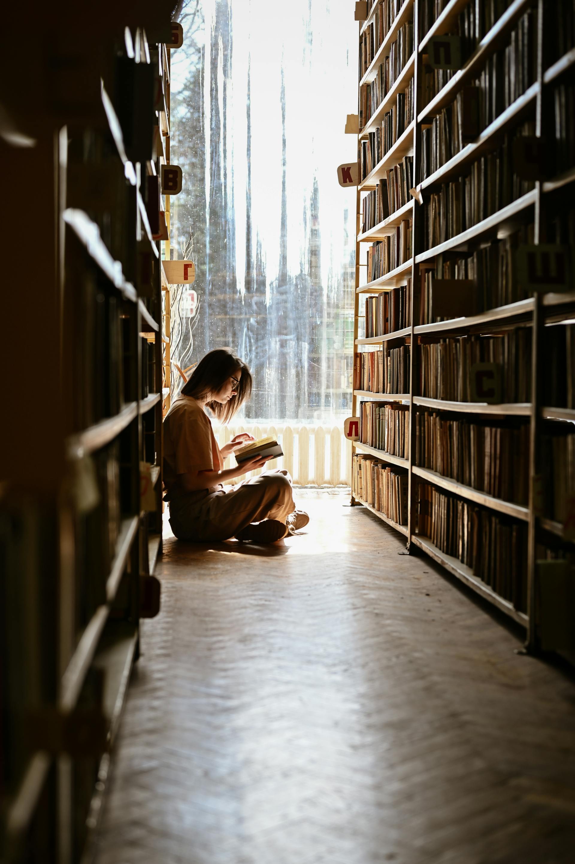 Una mujer sentada en el suelo leyendo un libro | Fuente: Pexels