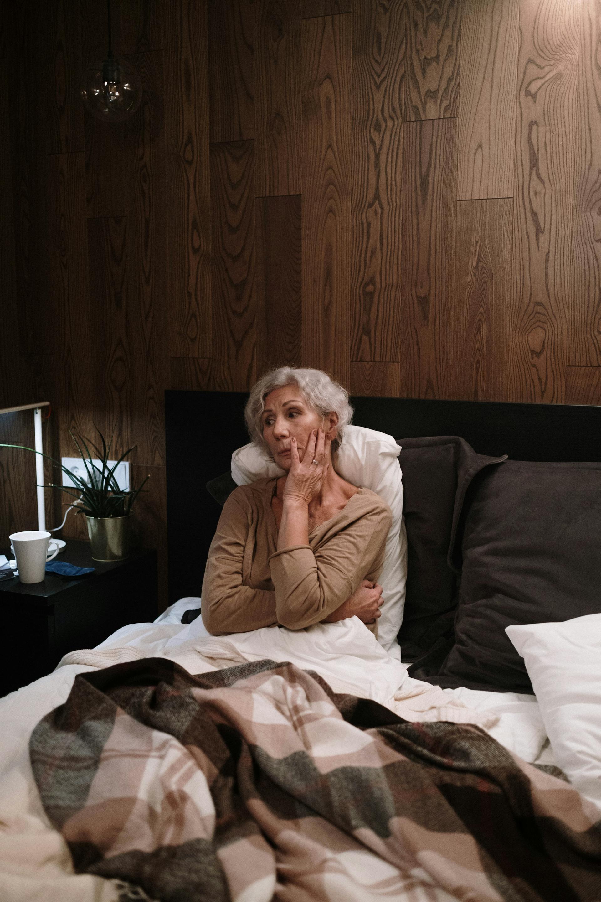 Una anciana triste sentada en la cama | Fuente: Pexels